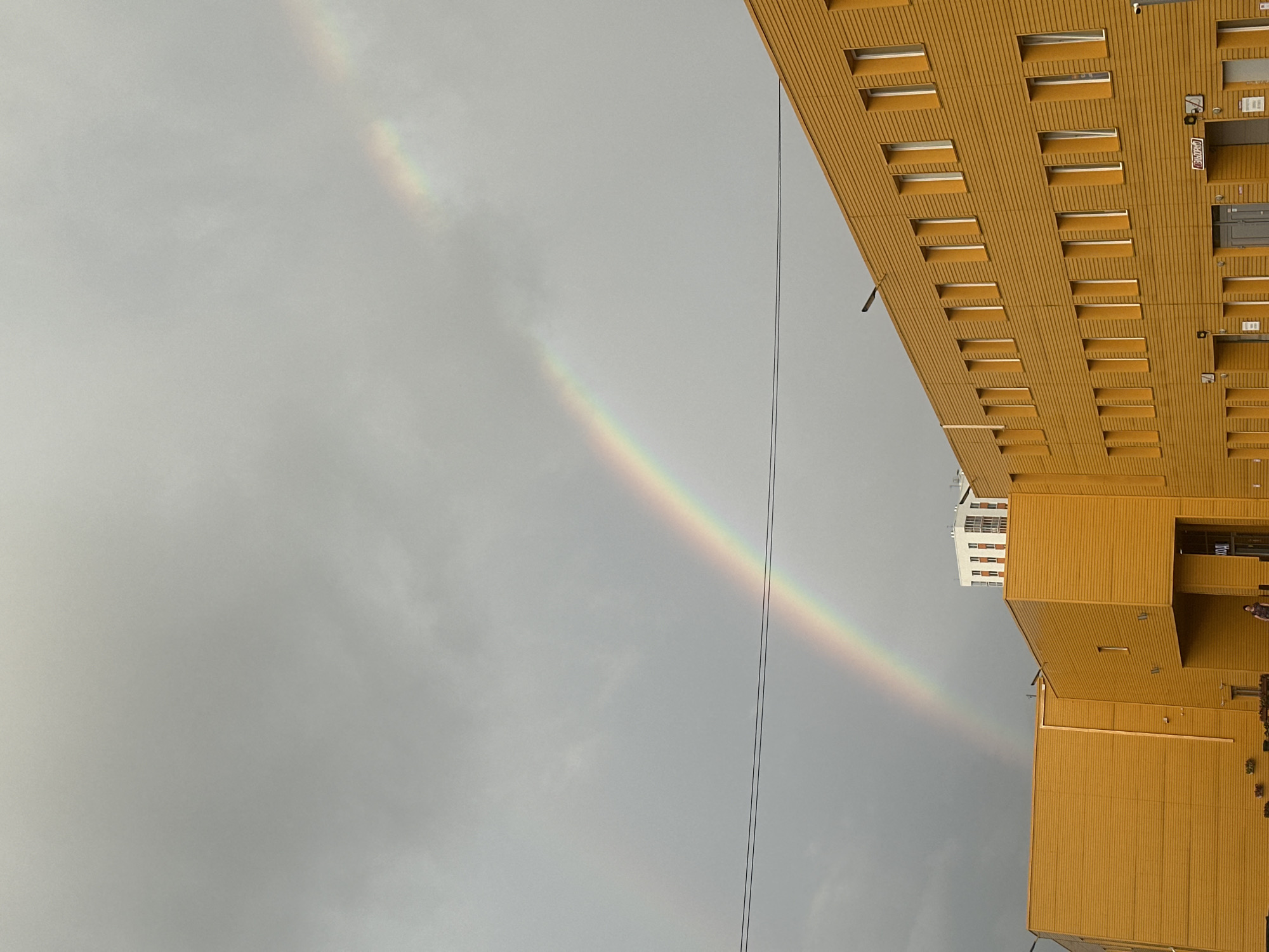 Rainbow over a yellow warehouse on a grey Perm afternoon