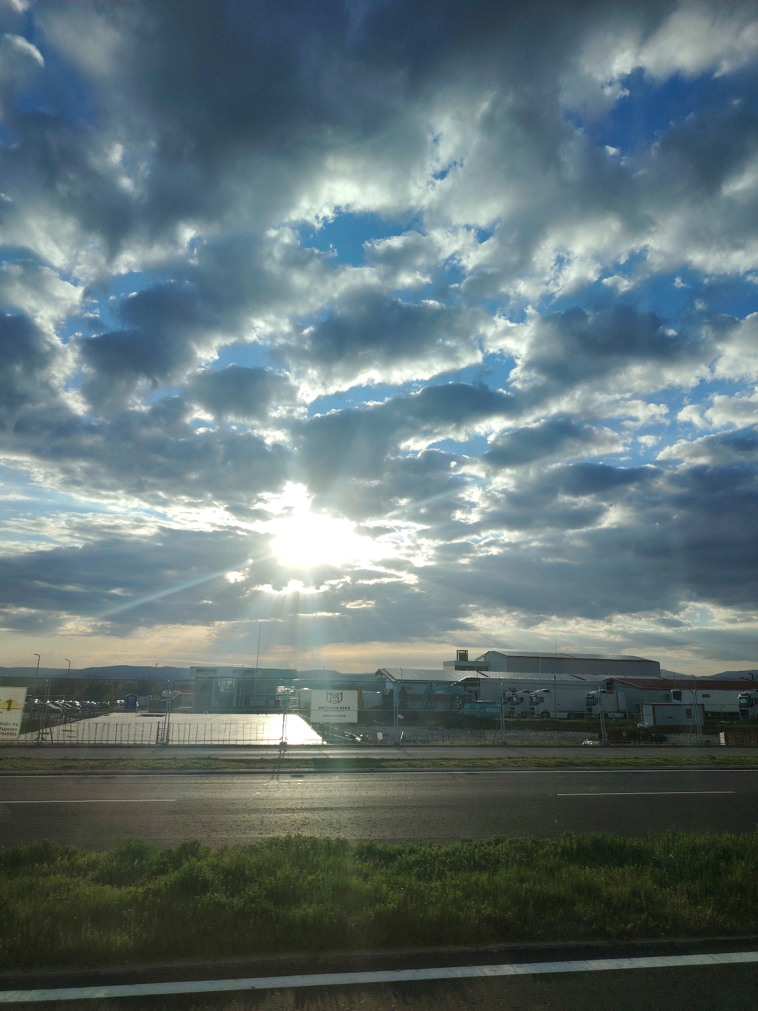 Morning sunlight breaks through clouds over Lyaskovets industrial road