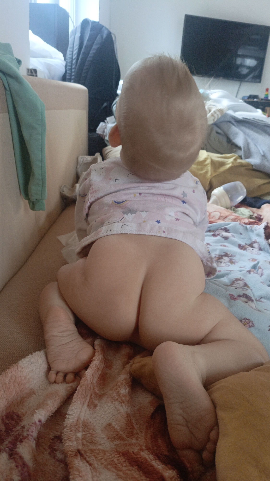Baby in unicorn shirt sits on sofa in Sarapul