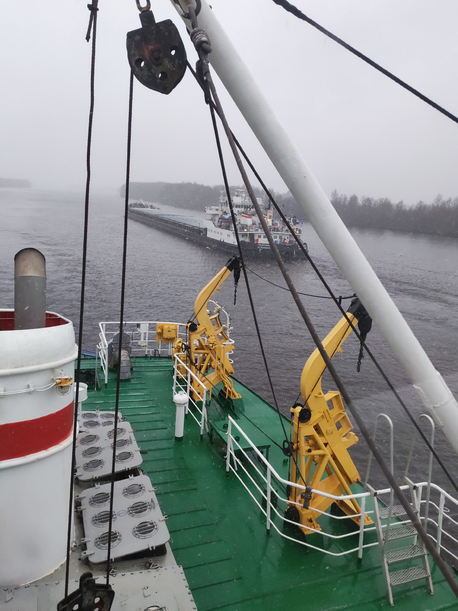 Commercial barge navigates Russian waterway during April snowfall