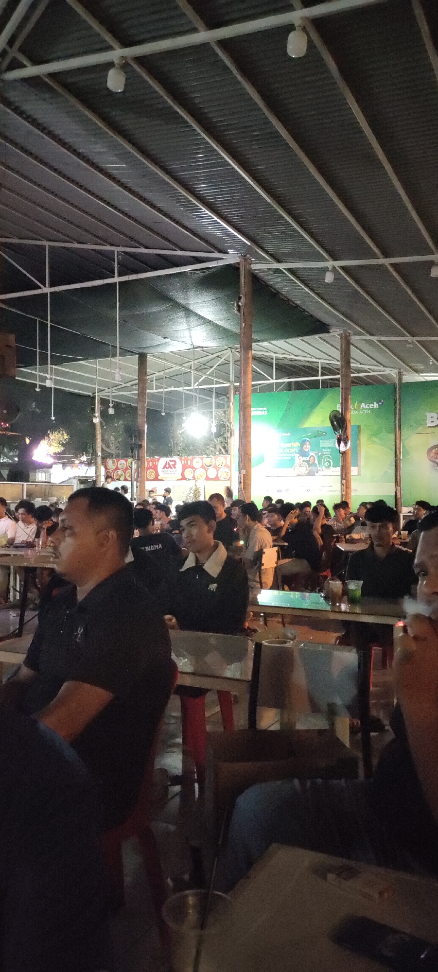 Banda Aceh cafe crowd watches a projected broadcast together
