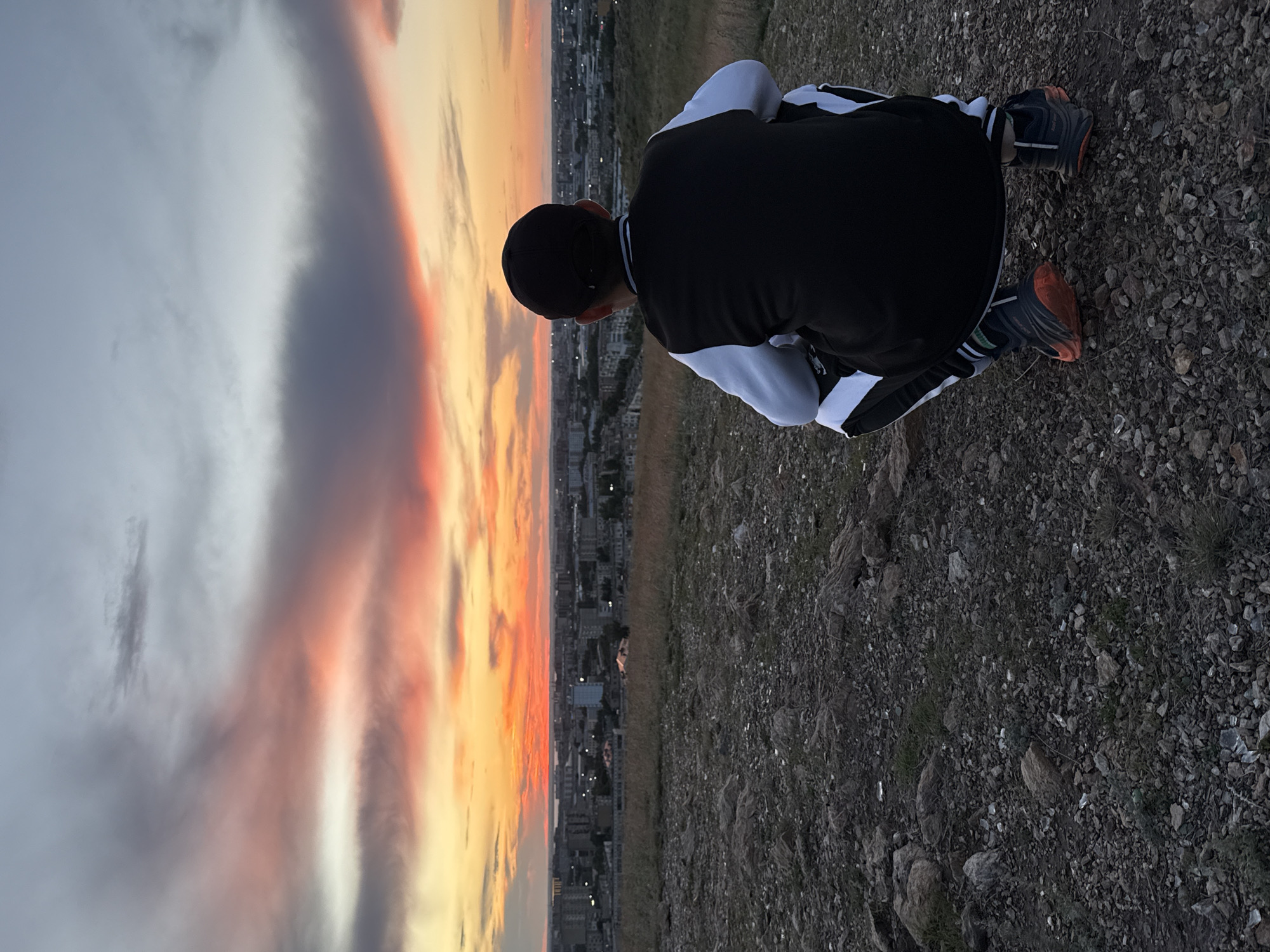 Young man watches sunset over Kokshetau from hillside overlook