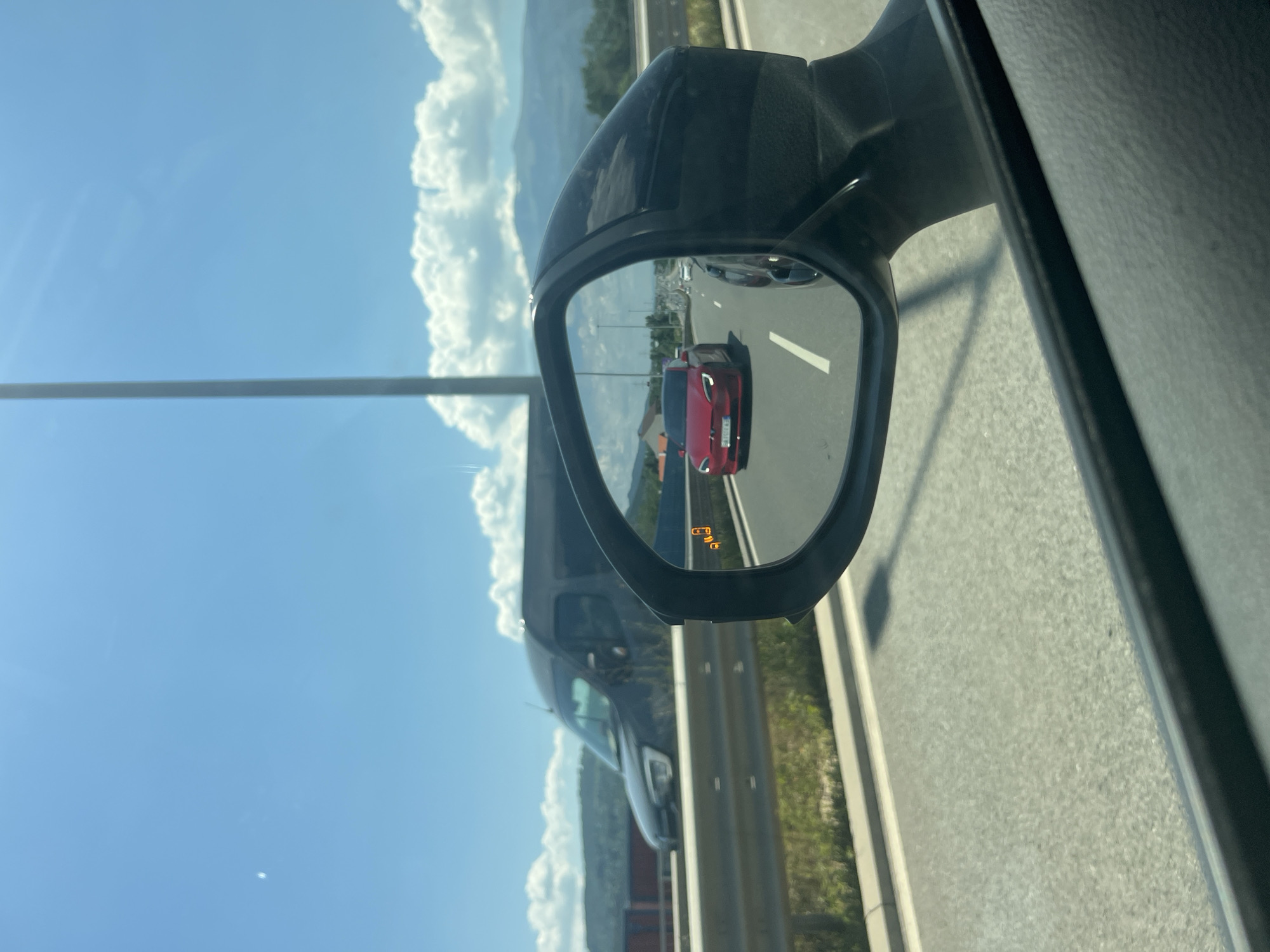 Red Tesla on a Sofia highway, seen through a side mirror