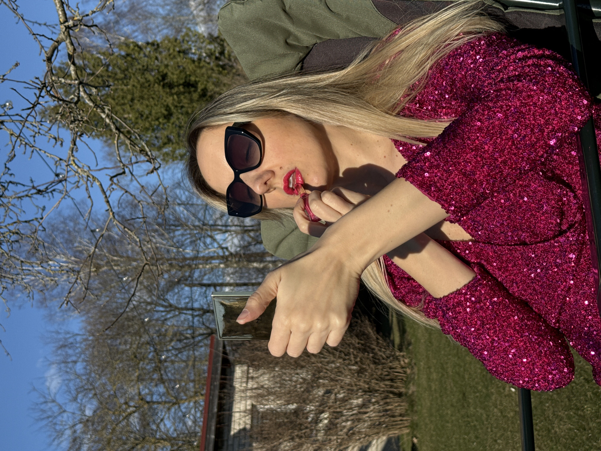 Woman in pink sequined dress poses with gardening tools