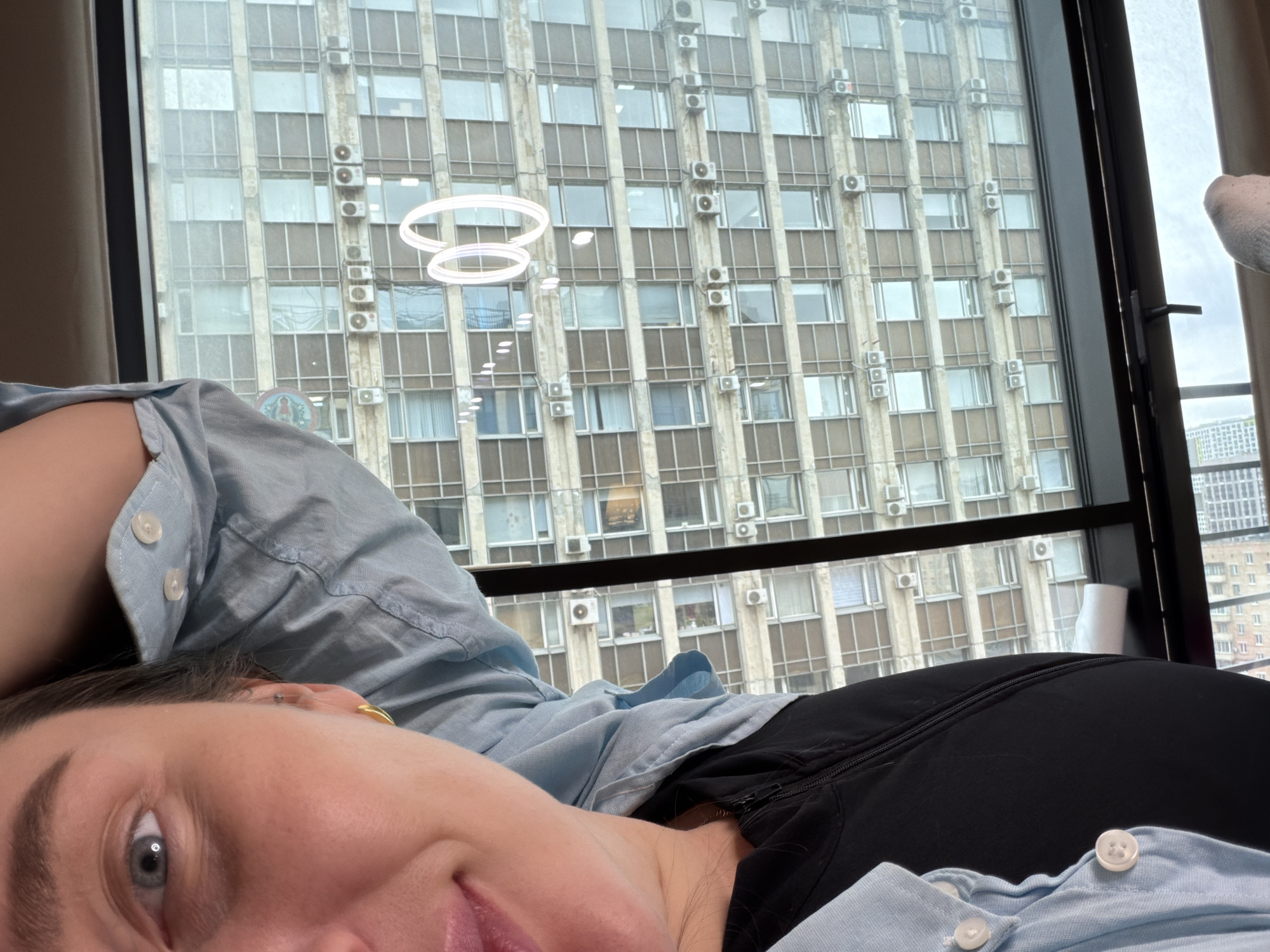 Woman rests indoors with Moscow cityscape visible through window