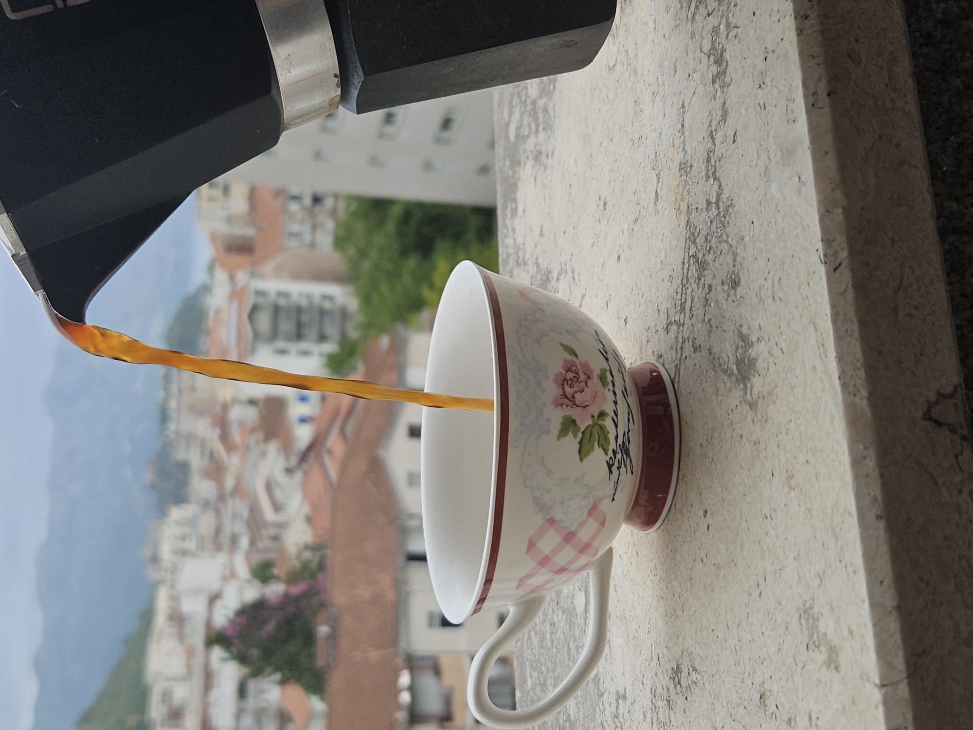 Moka pot coffee poured over a misty city with red rooftops