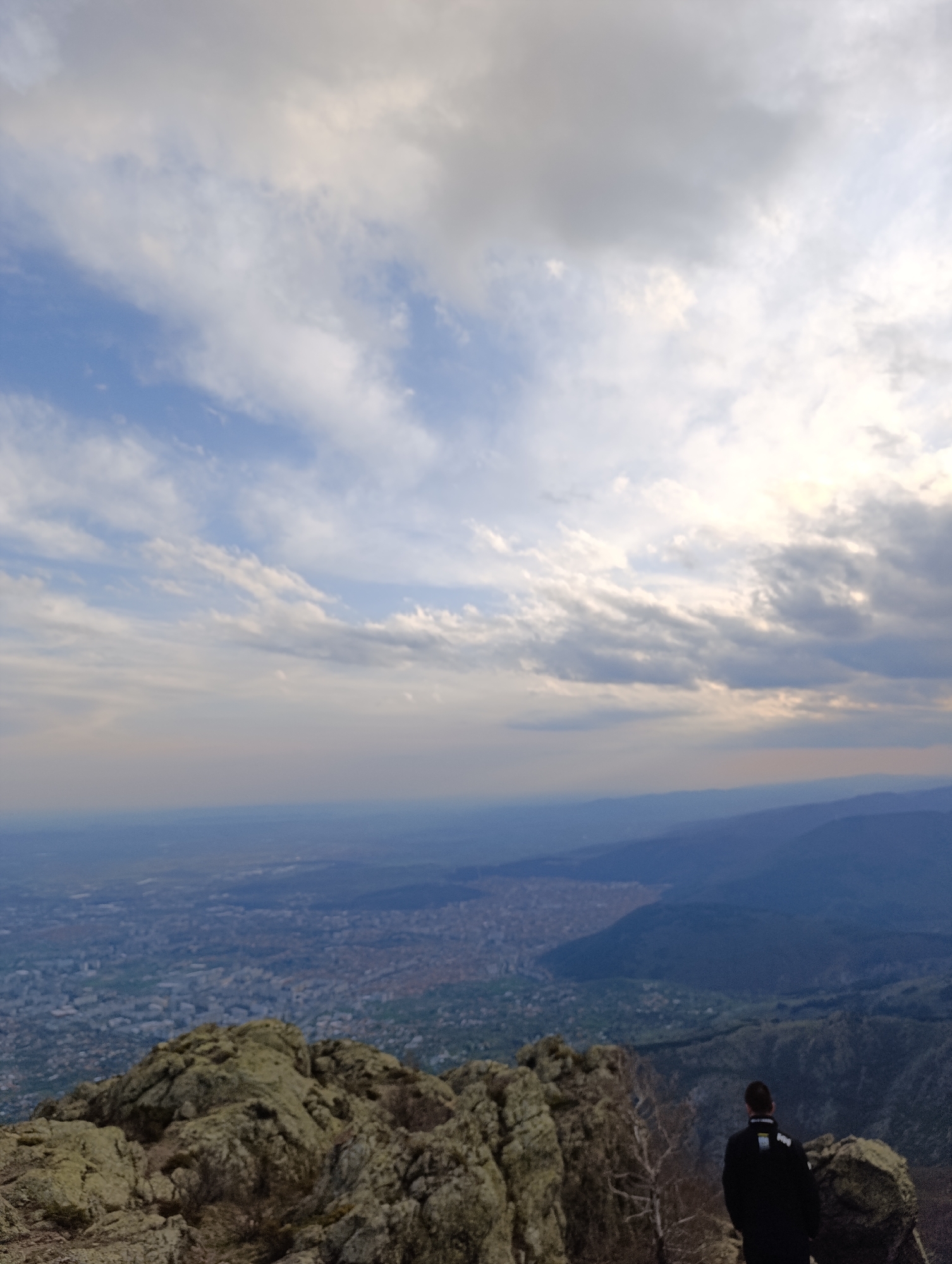 Person observes Ichera cityscape from rocky mountain terrain