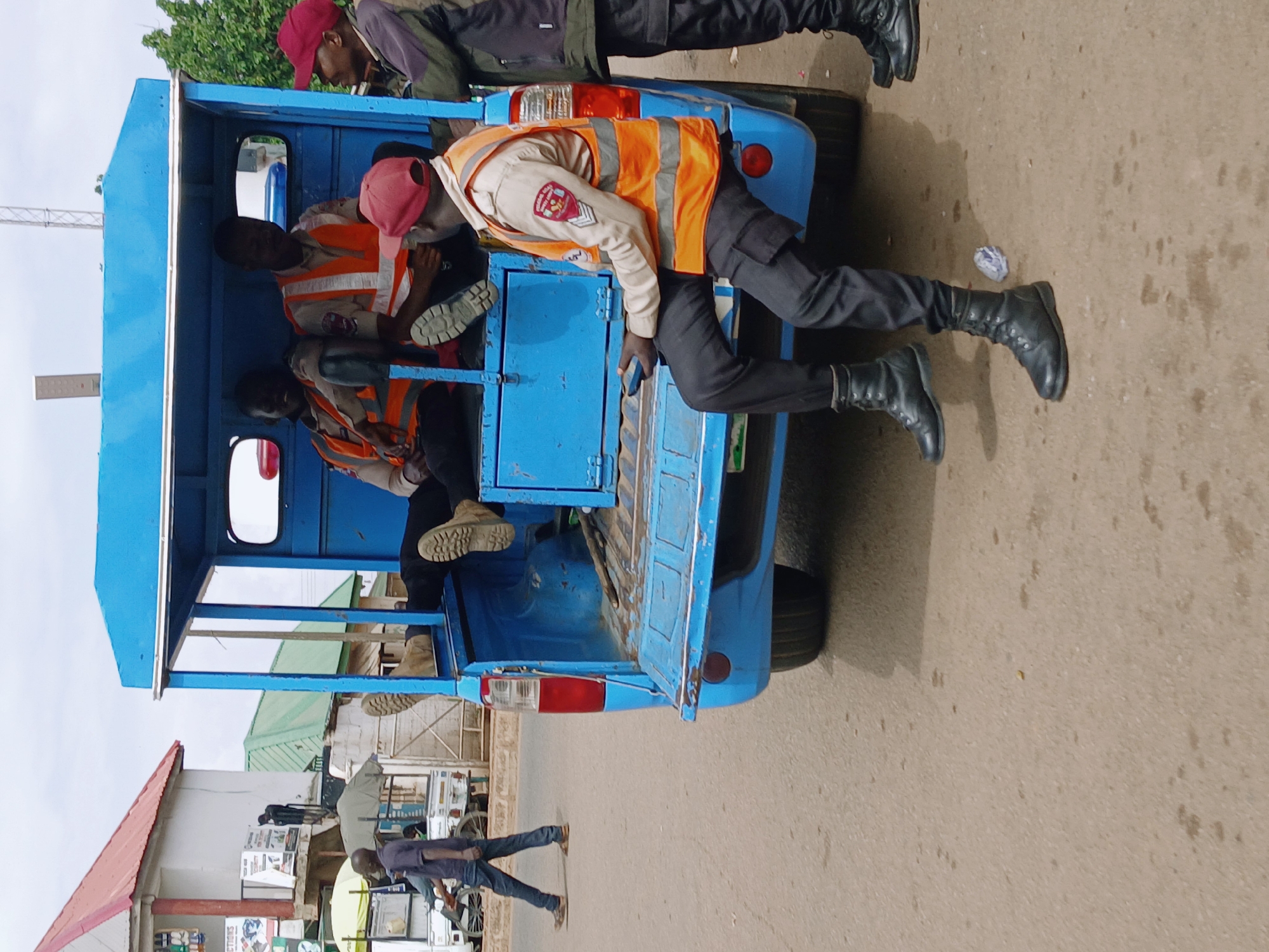 Blue vehicle carries passengers in orange vests, red hats