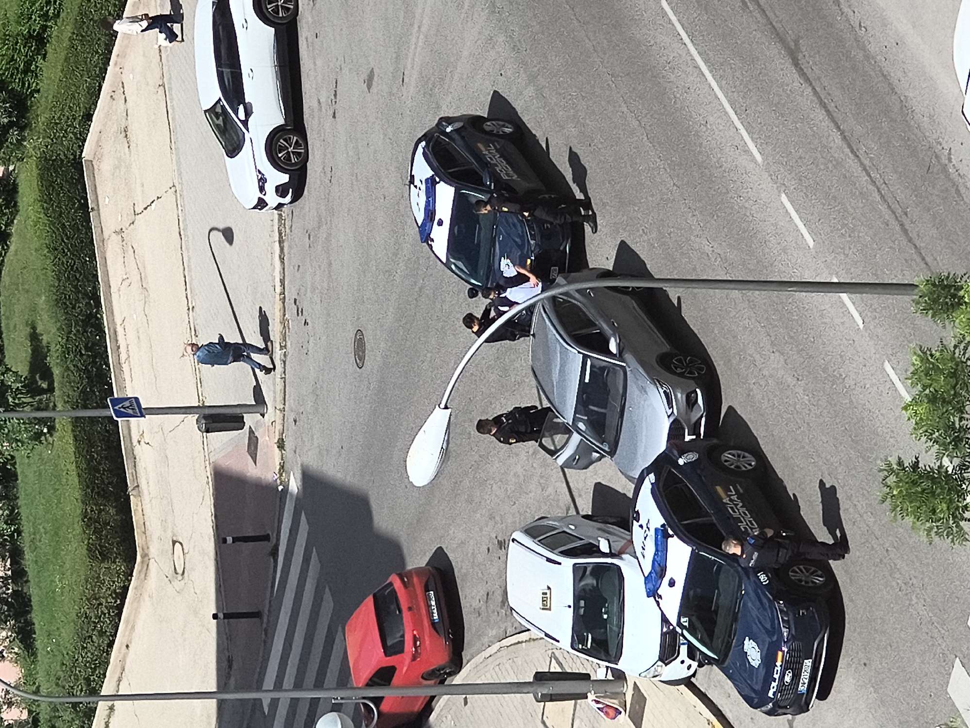 Police vehicles patrol Madrid street amid regular traffic