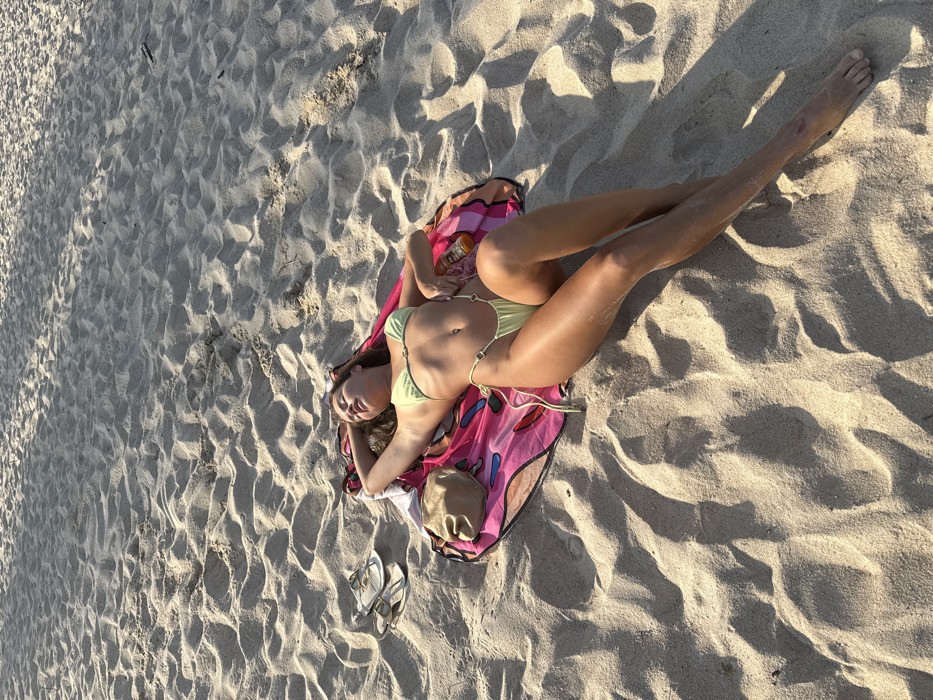 Woman rests on butterfly-patterned towel at Thai beach