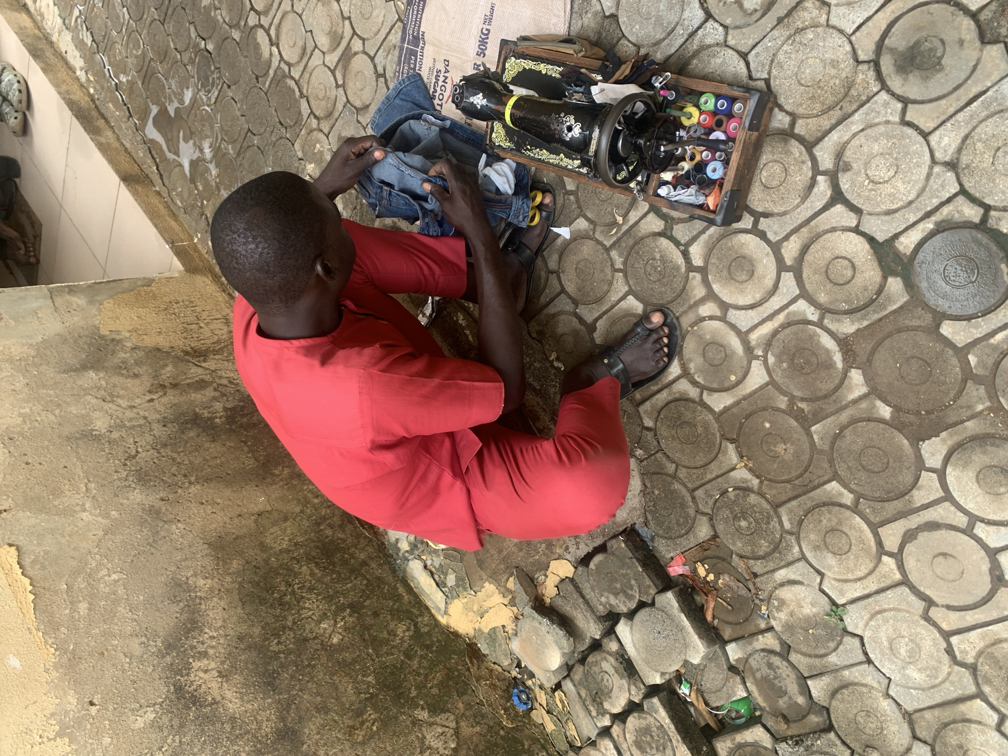 Street tailor operates vintage sewing machine outdoors in Abuja