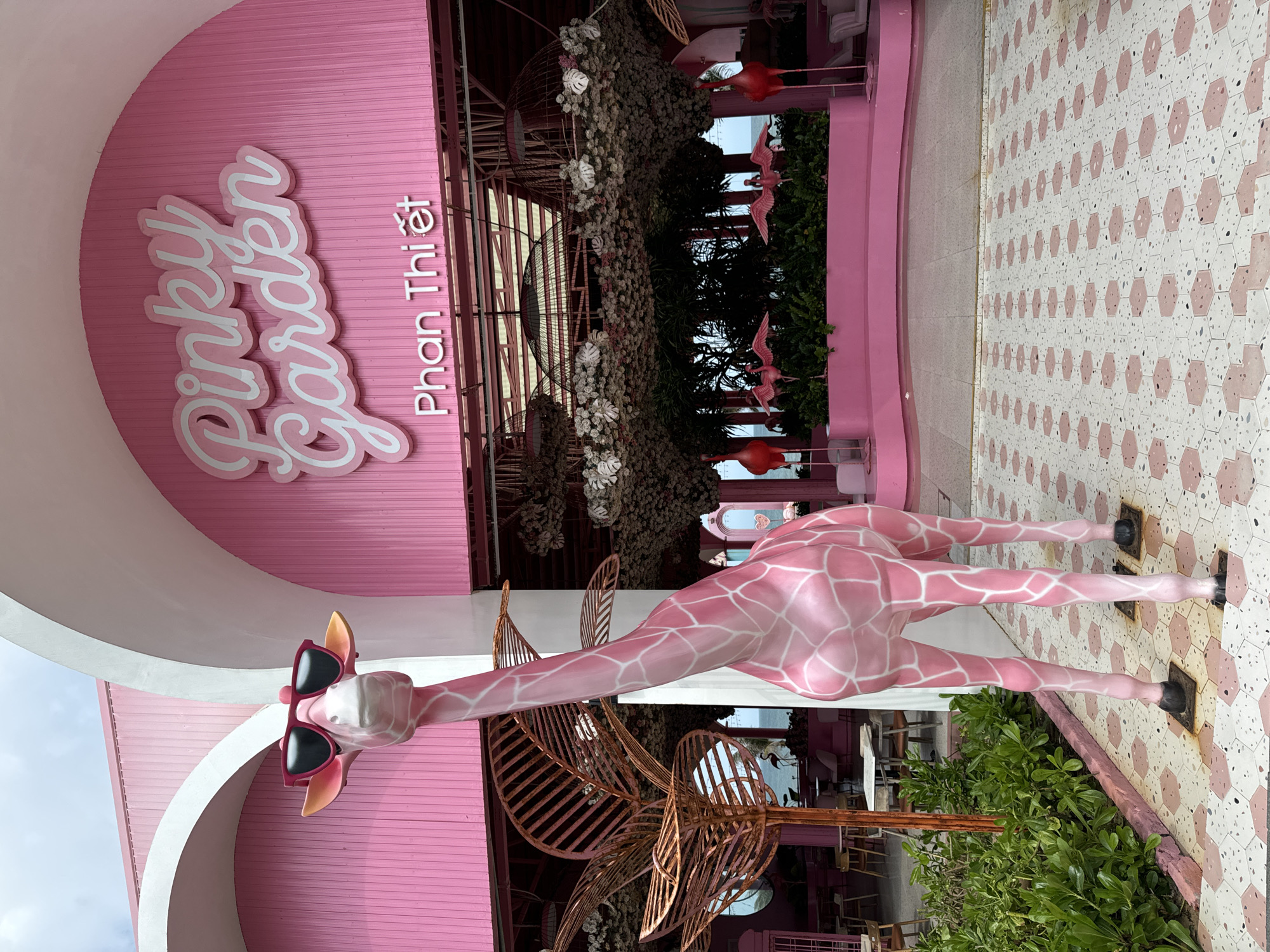 Visitors document pink-themed Pinky Garden cafe with giraffe statues