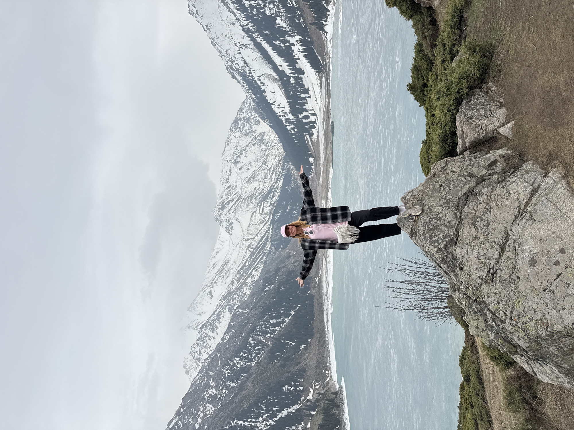 Woman poses at partially frozen Big Almaty Lake