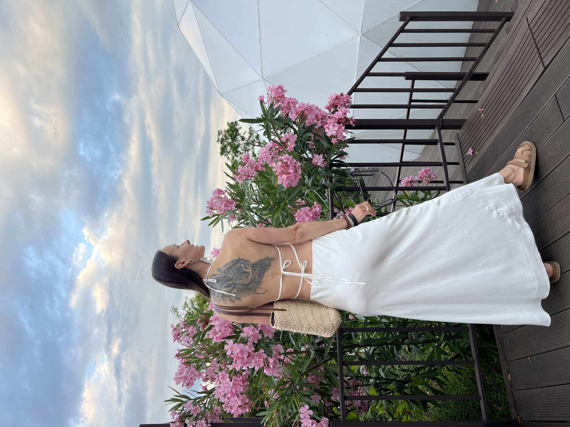 White dress and pink flowers on a cloudy Sochi deck