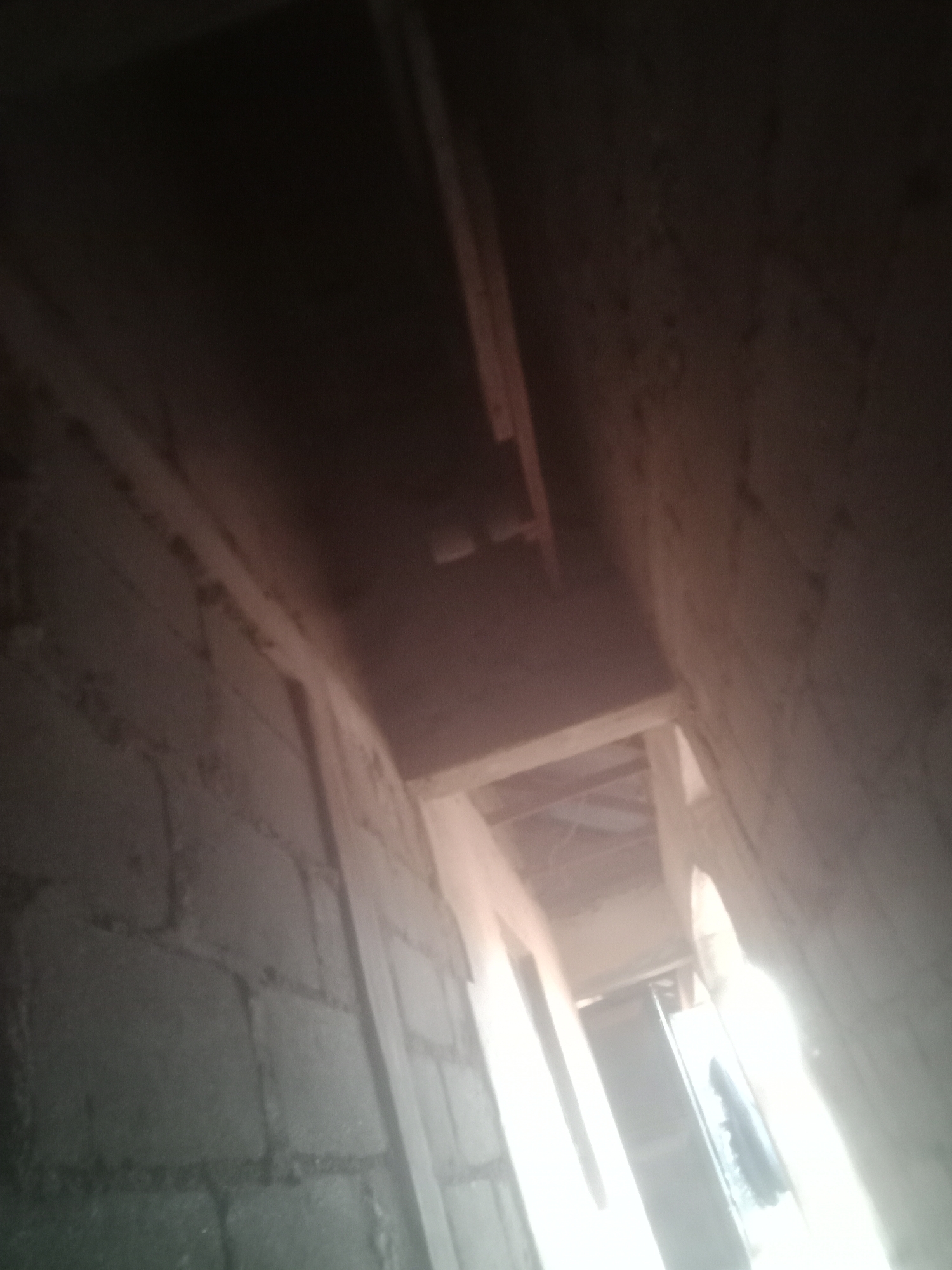 Inside an unfinished building — bare brick walls and open ceiling shaft