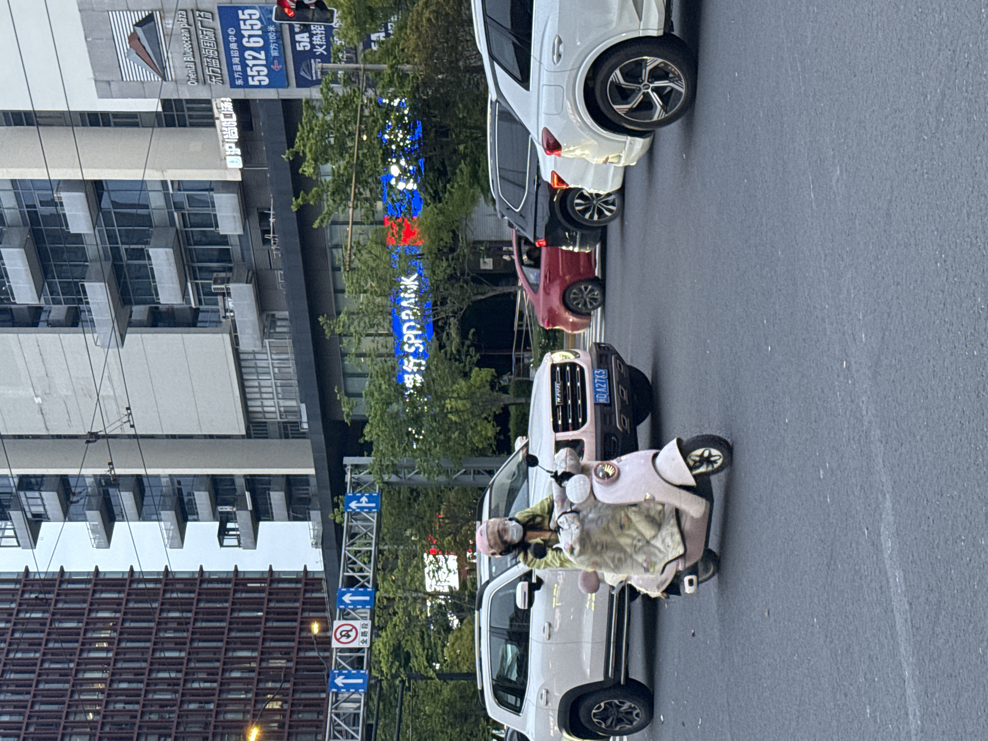 Pink scooter rider navigates busy Shanghai intersection under overcast skies