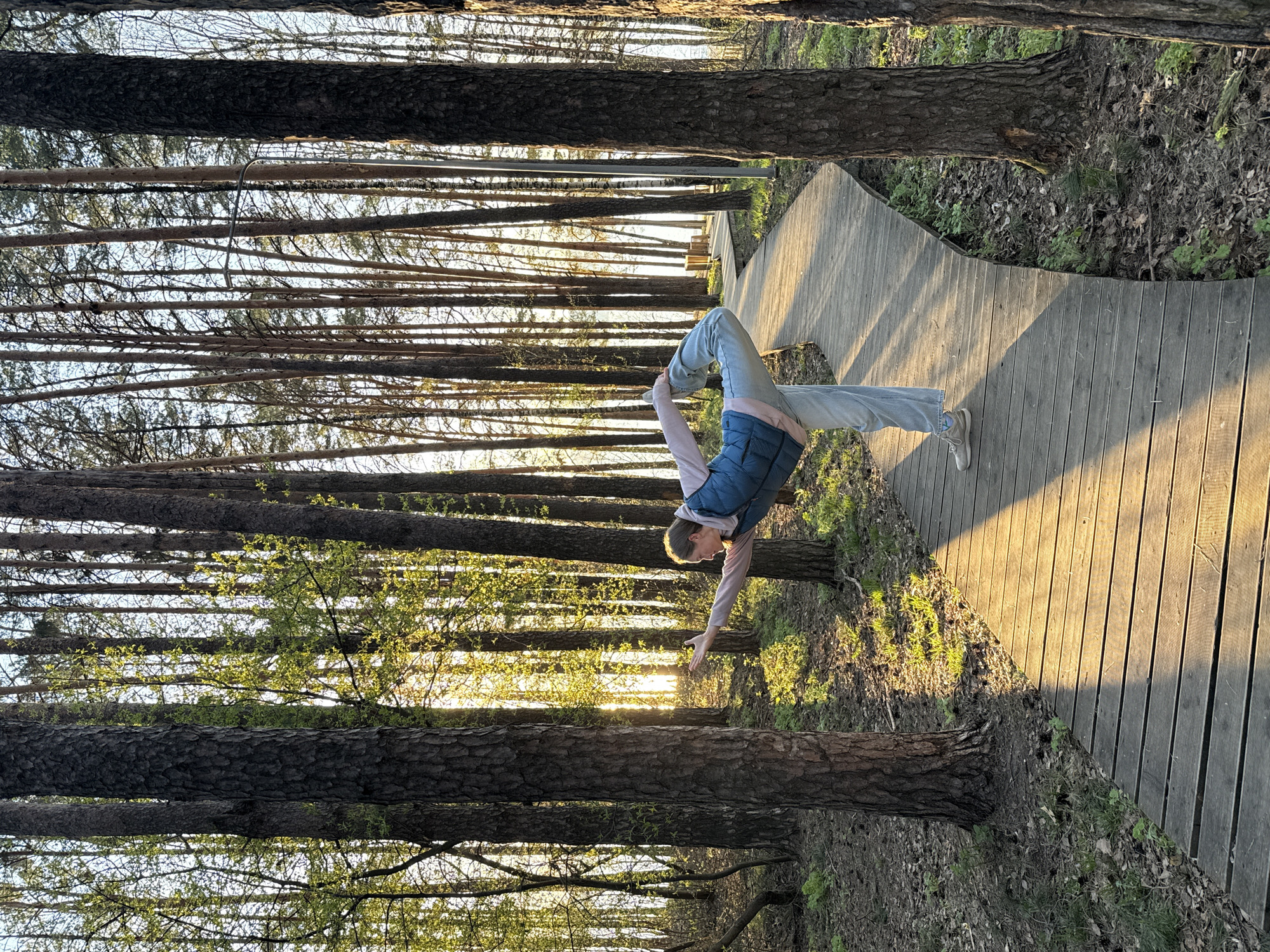 Woman practices yoga on forest boardwalk near water in Russia