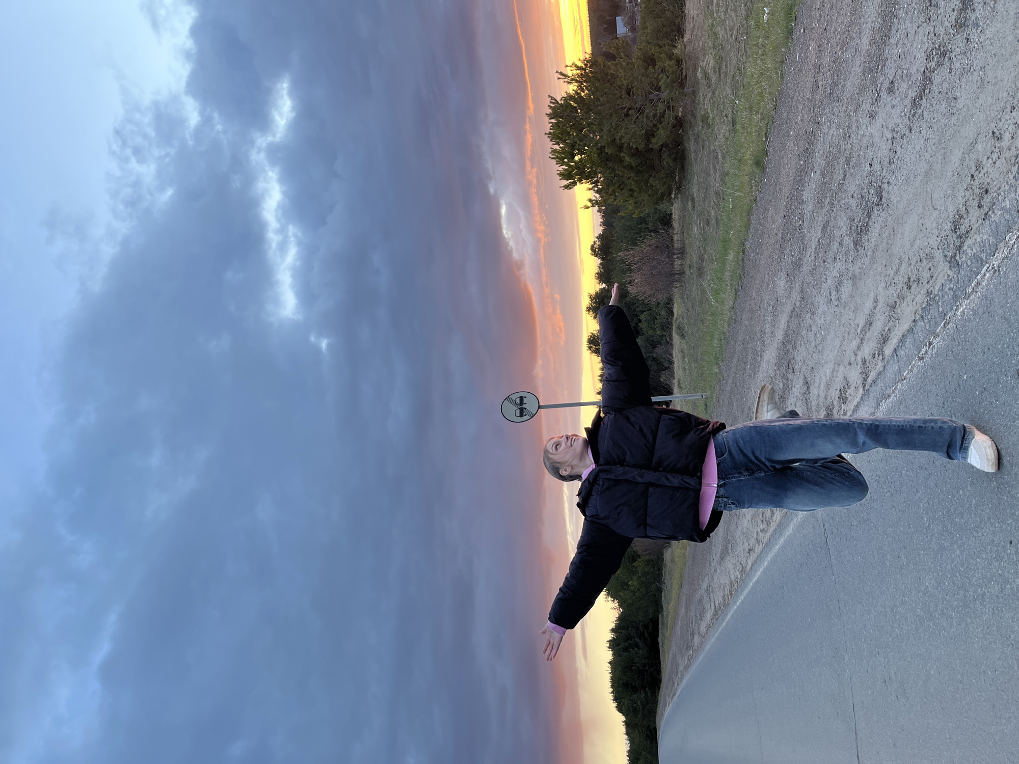 Young person stands on Russian road during dramatic sunset