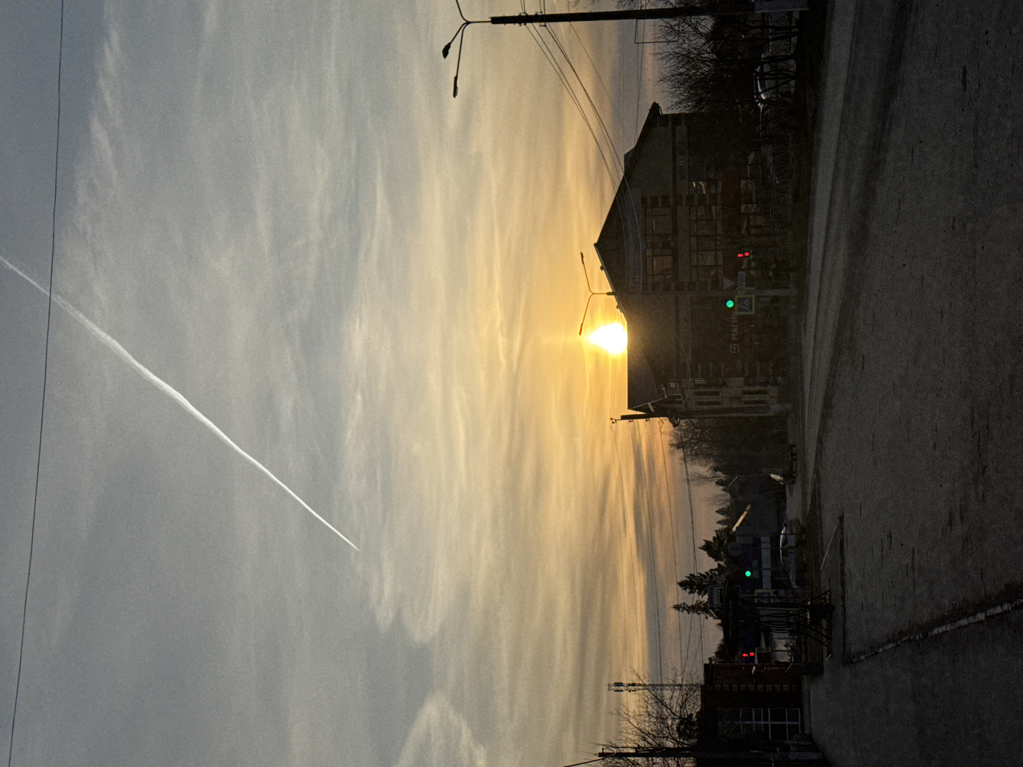 Sunset street scene with contrail observed in Chernushka, Russia