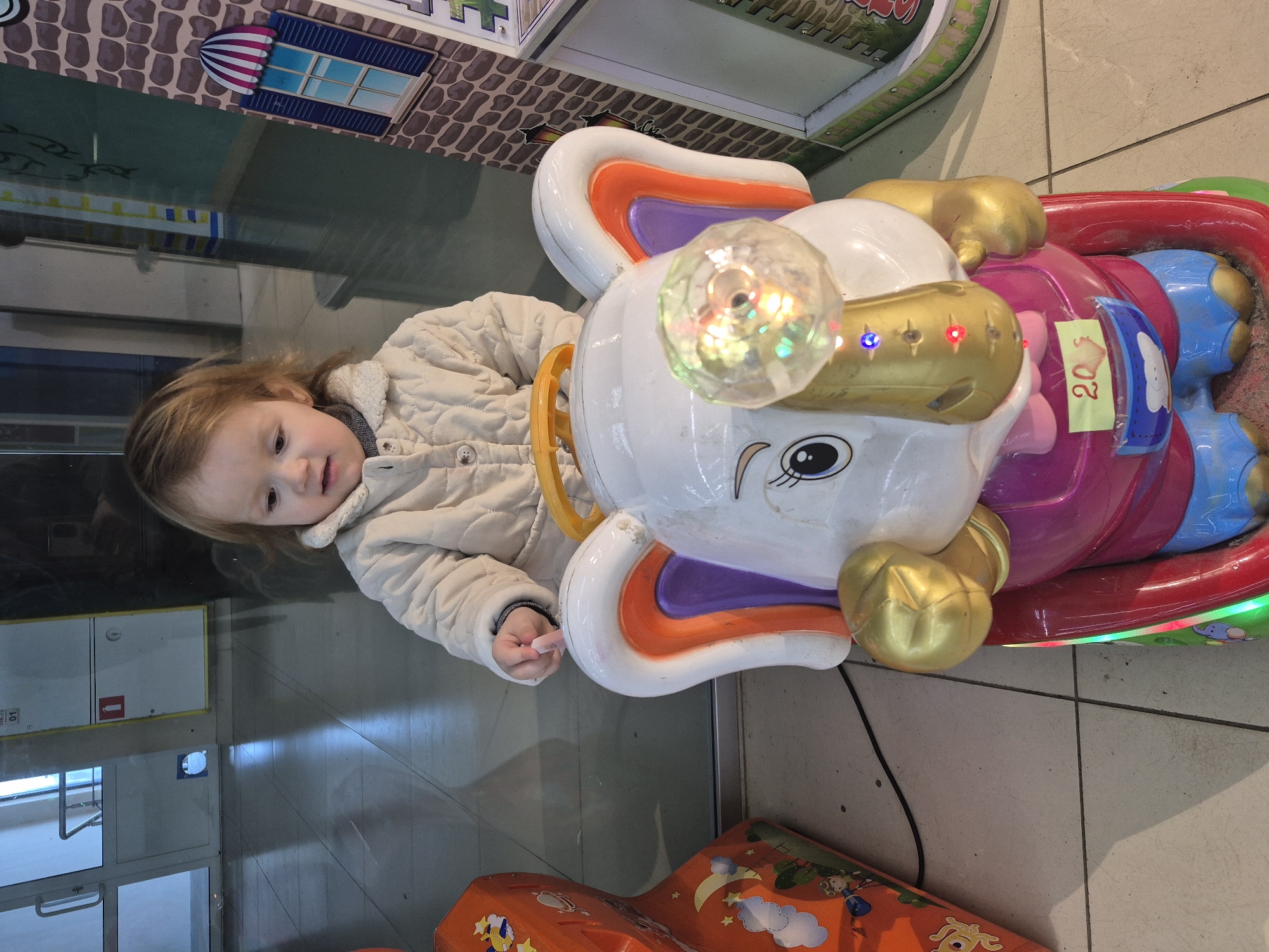 Toddler enjoys arcade rides at indoor mall playground