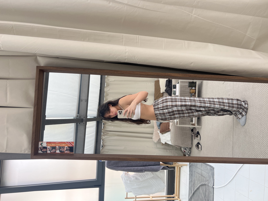 Woman photographs herself in Milan bedroom wearing white athletic wear
