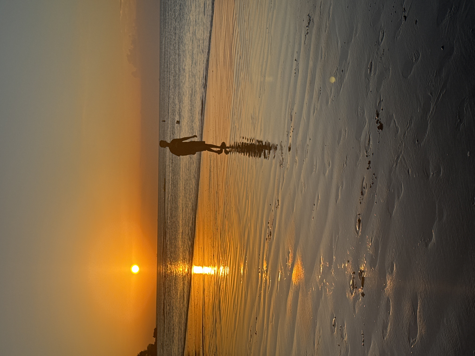 Sunset beach scene with crowds, games, and golden light