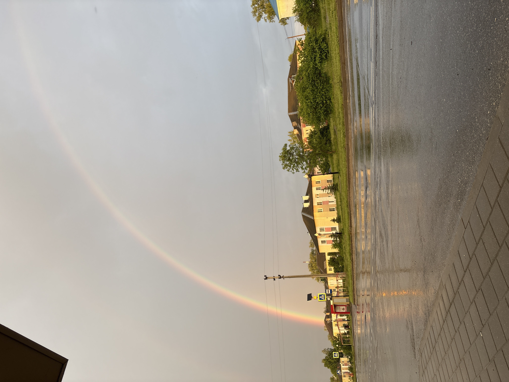 Rainbow appears over wet city streets after rainfall