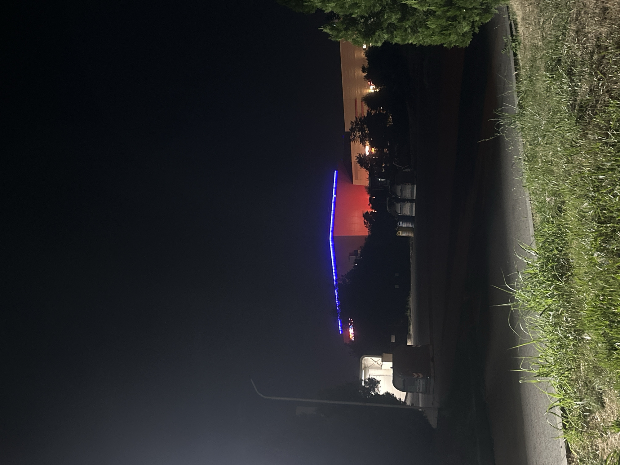 Tesla parked at night near neon-lit shops in Ruse, Bulgaria