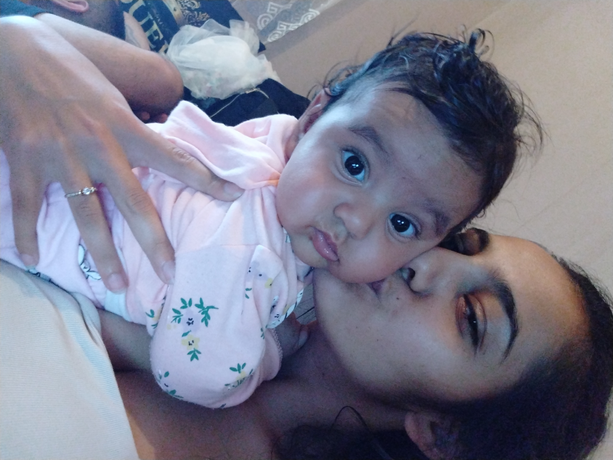 Mother kisses baby in pink floral outfit during tender moment