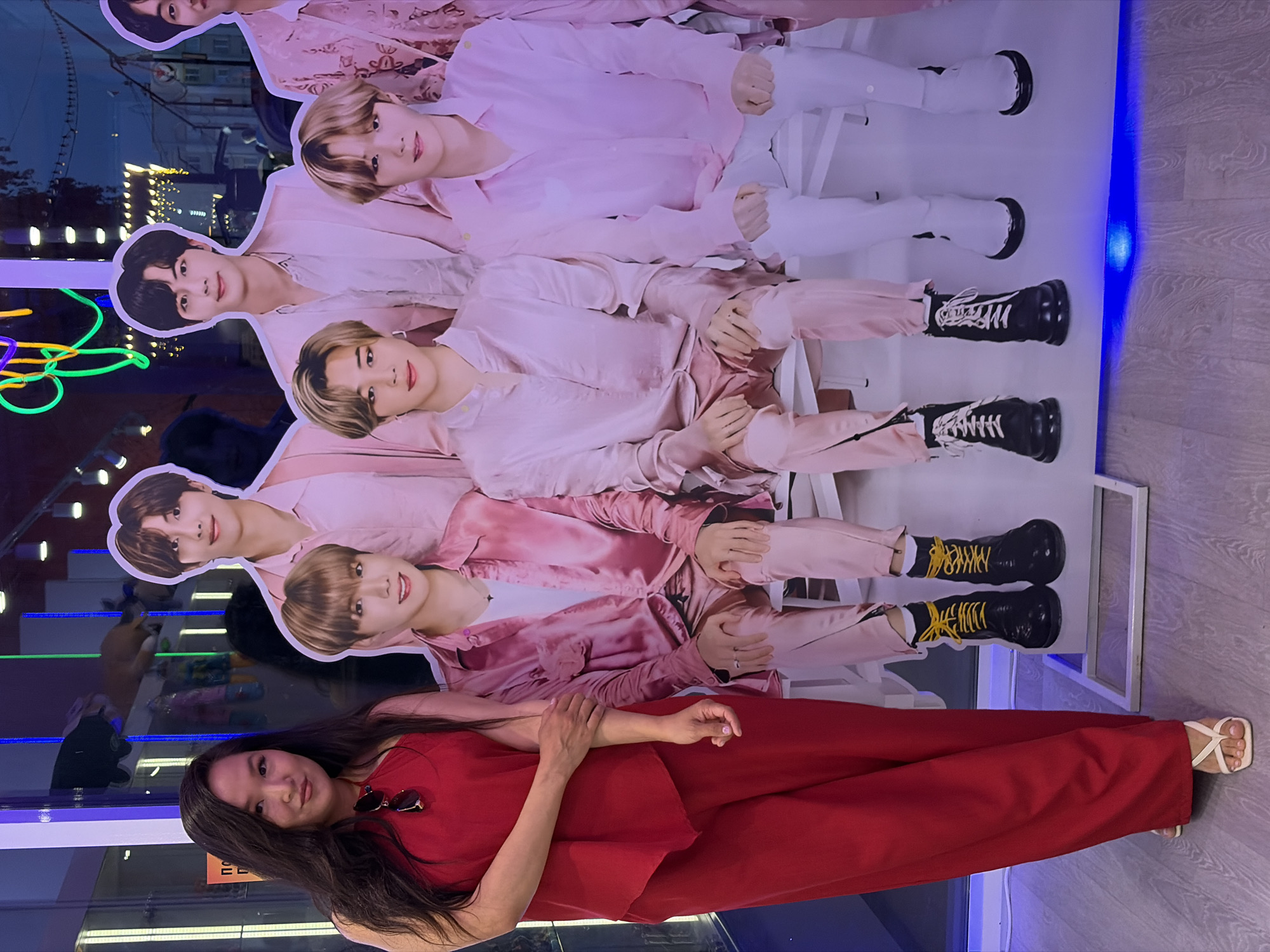 Woman in red dress lies before BTS poster