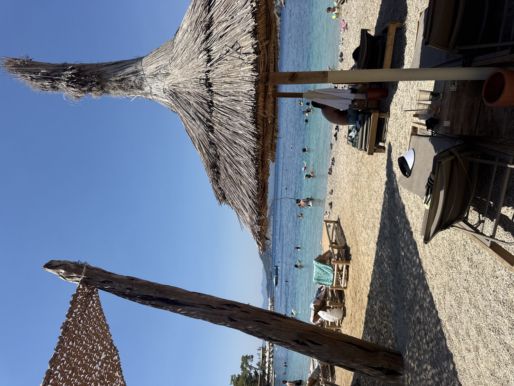 Packed pebble beach day in Fethiye under summer sun