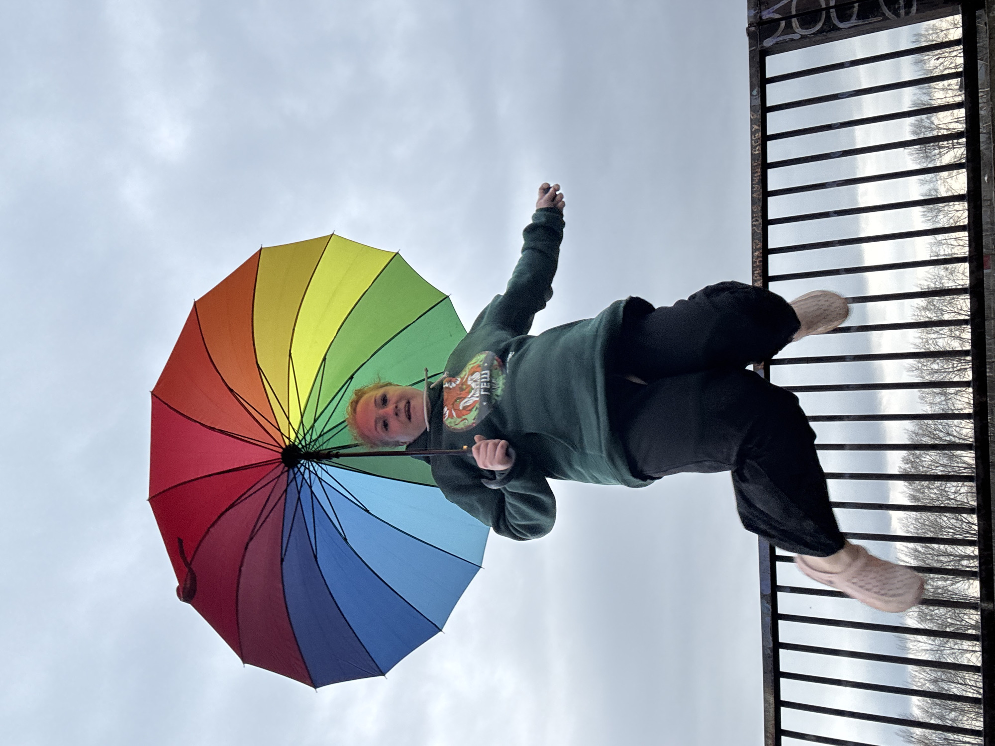 Woman with rainbow umbrella photographed by water in Chaikovsky
