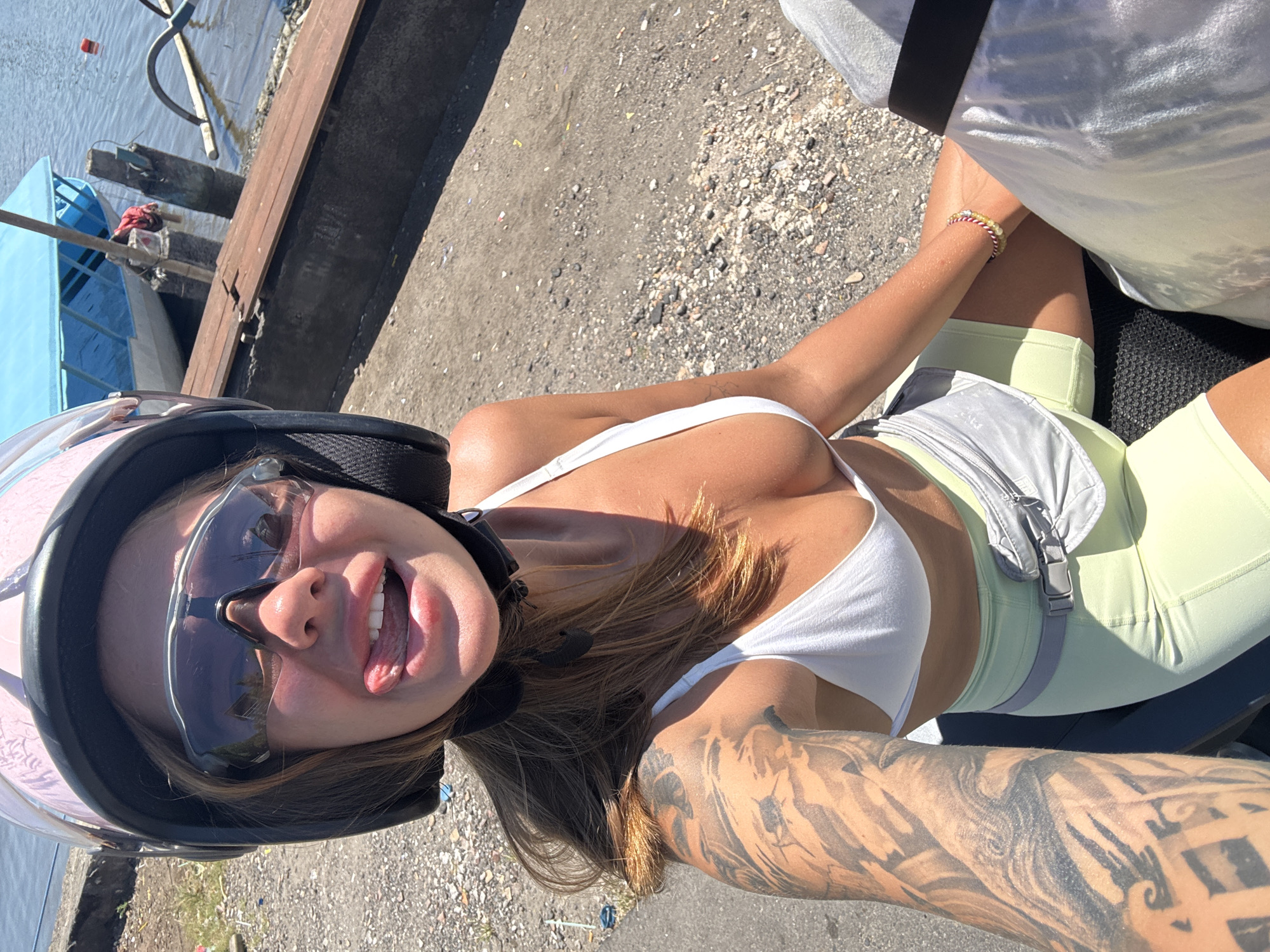 Woman photographs herself on motorcycle near Denpasar harbor