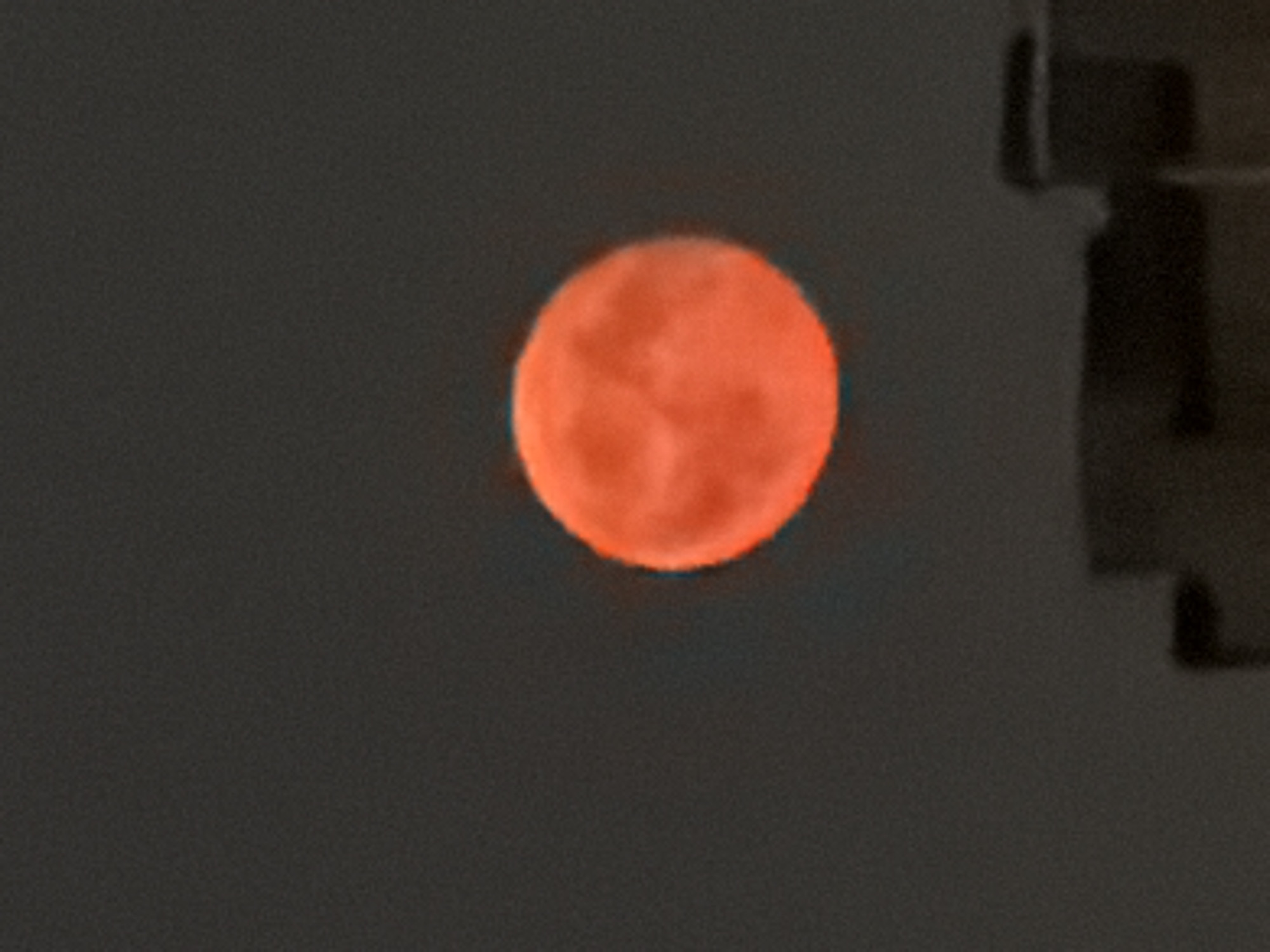 Blood moon rises over a city skyline at night