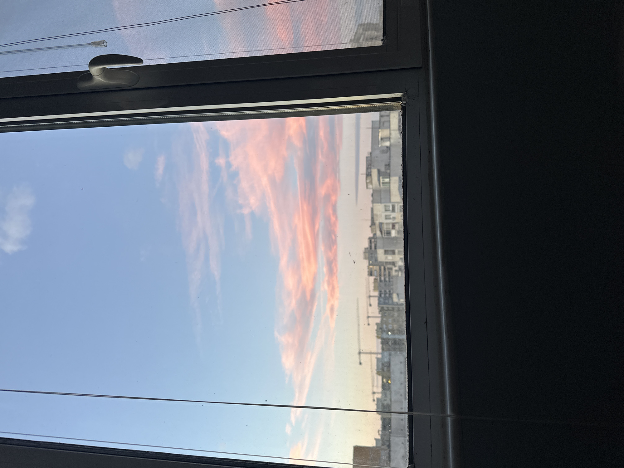 Person photographs cloudy sky through window in Plovdiv