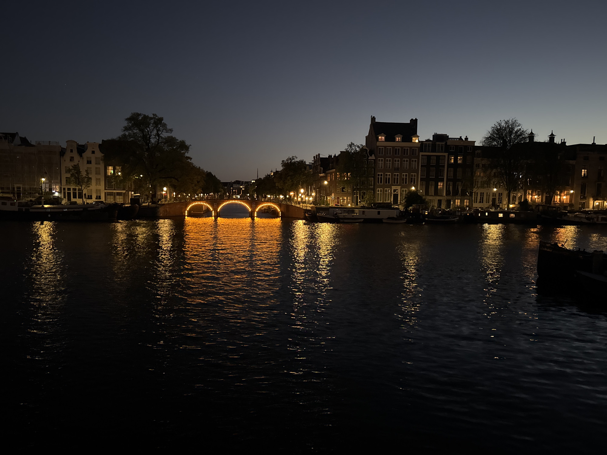 Amsterdam canals at dusk, bridges and a docked boat