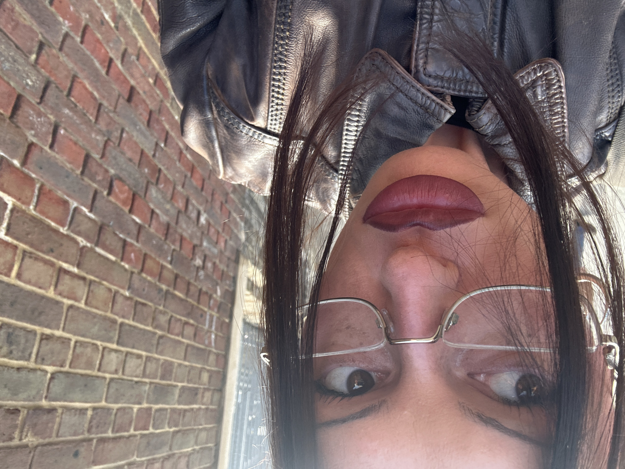 Upside-down selfie captured against brick wall in Tonbridge area