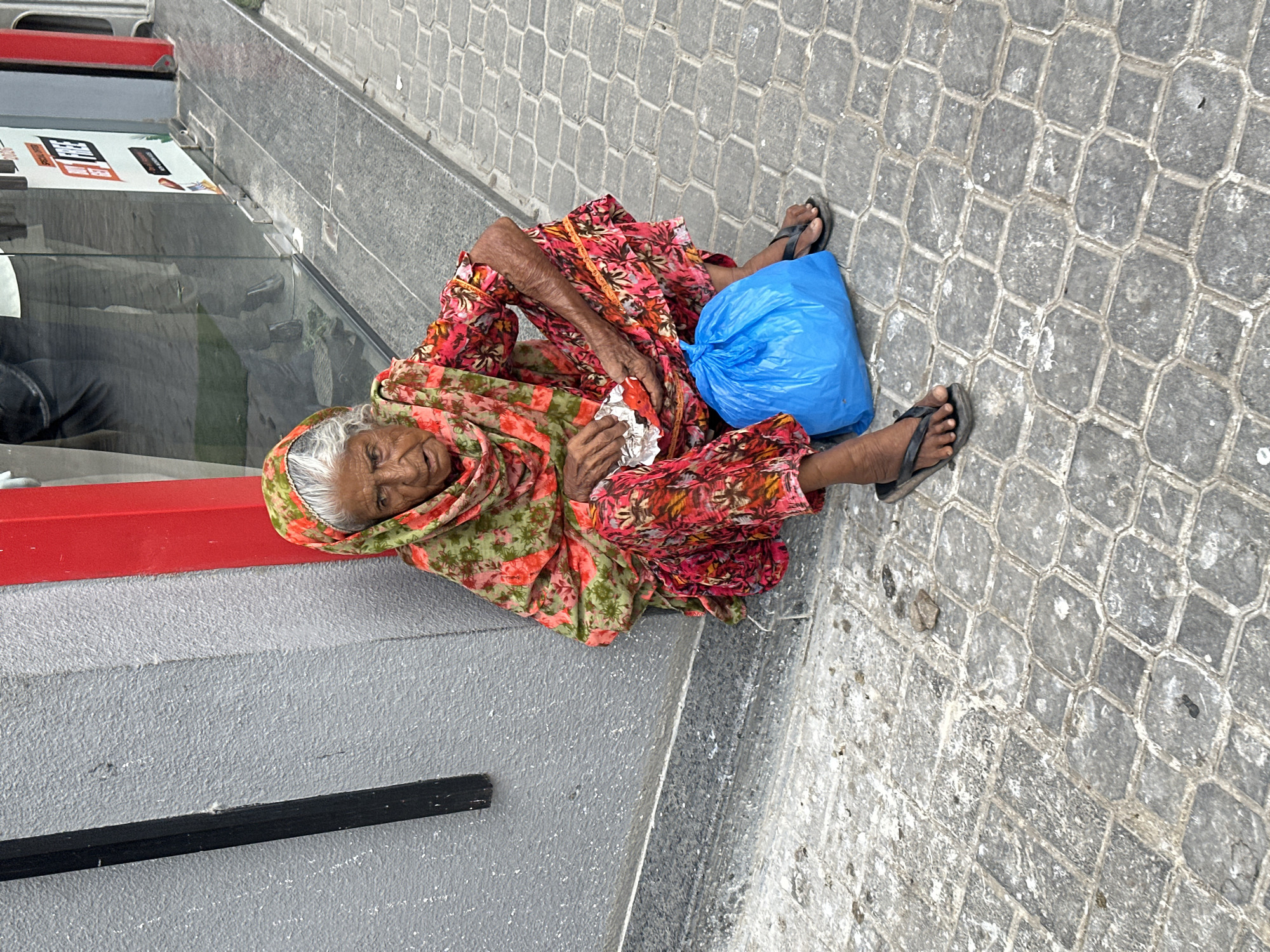 Resting against a wall in Karachi, dressed in floral shalwar kameez