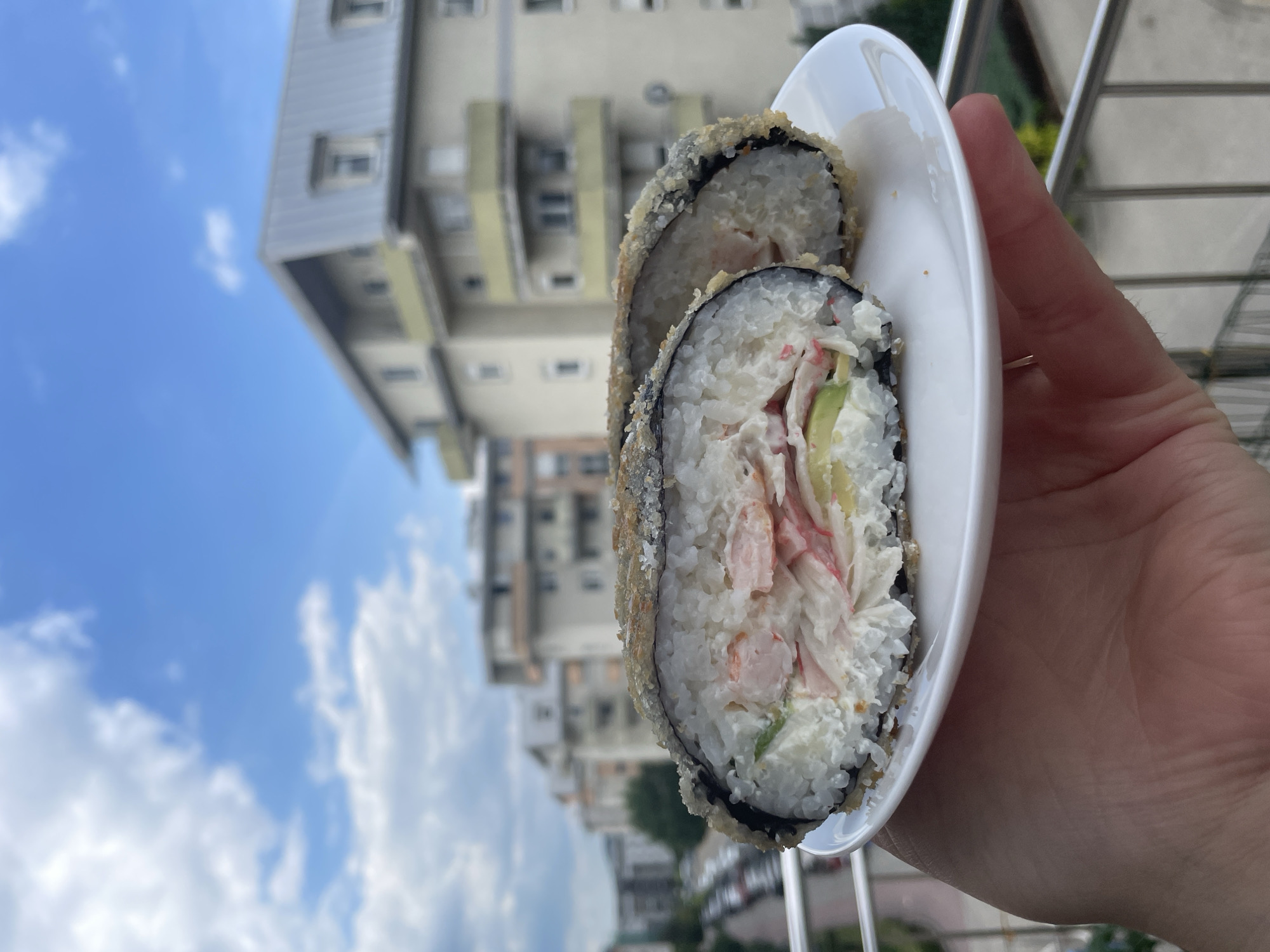 Outdoor lunch featuring deep-fried sushi rolls and beverages documented