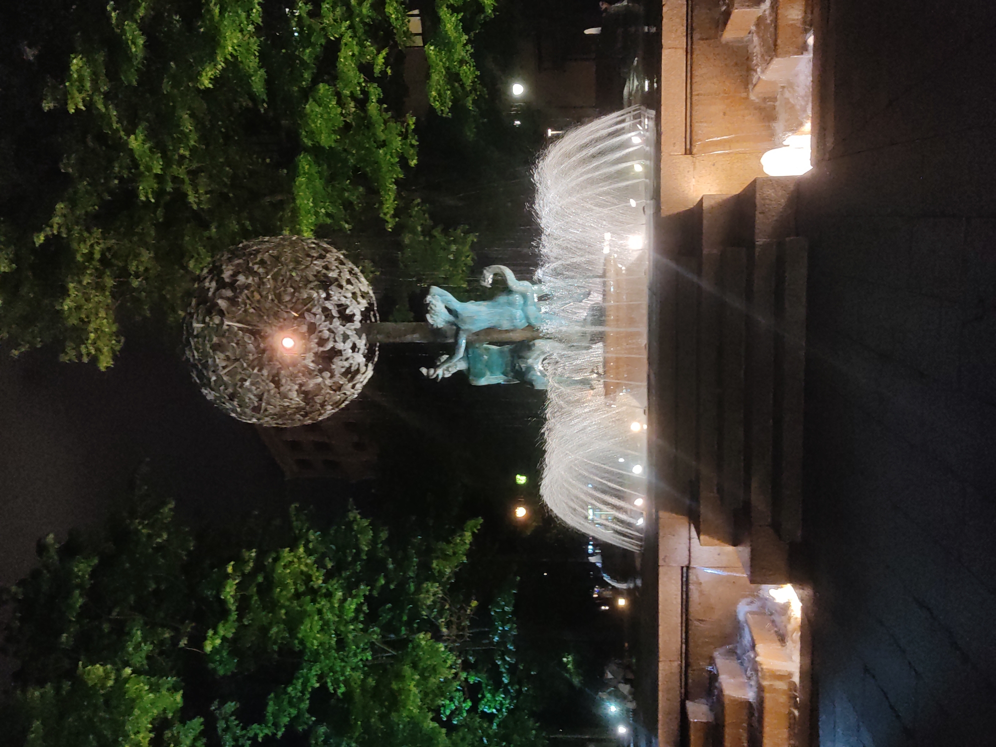 Illuminated Moscow fountain with sculptural figures observed at night