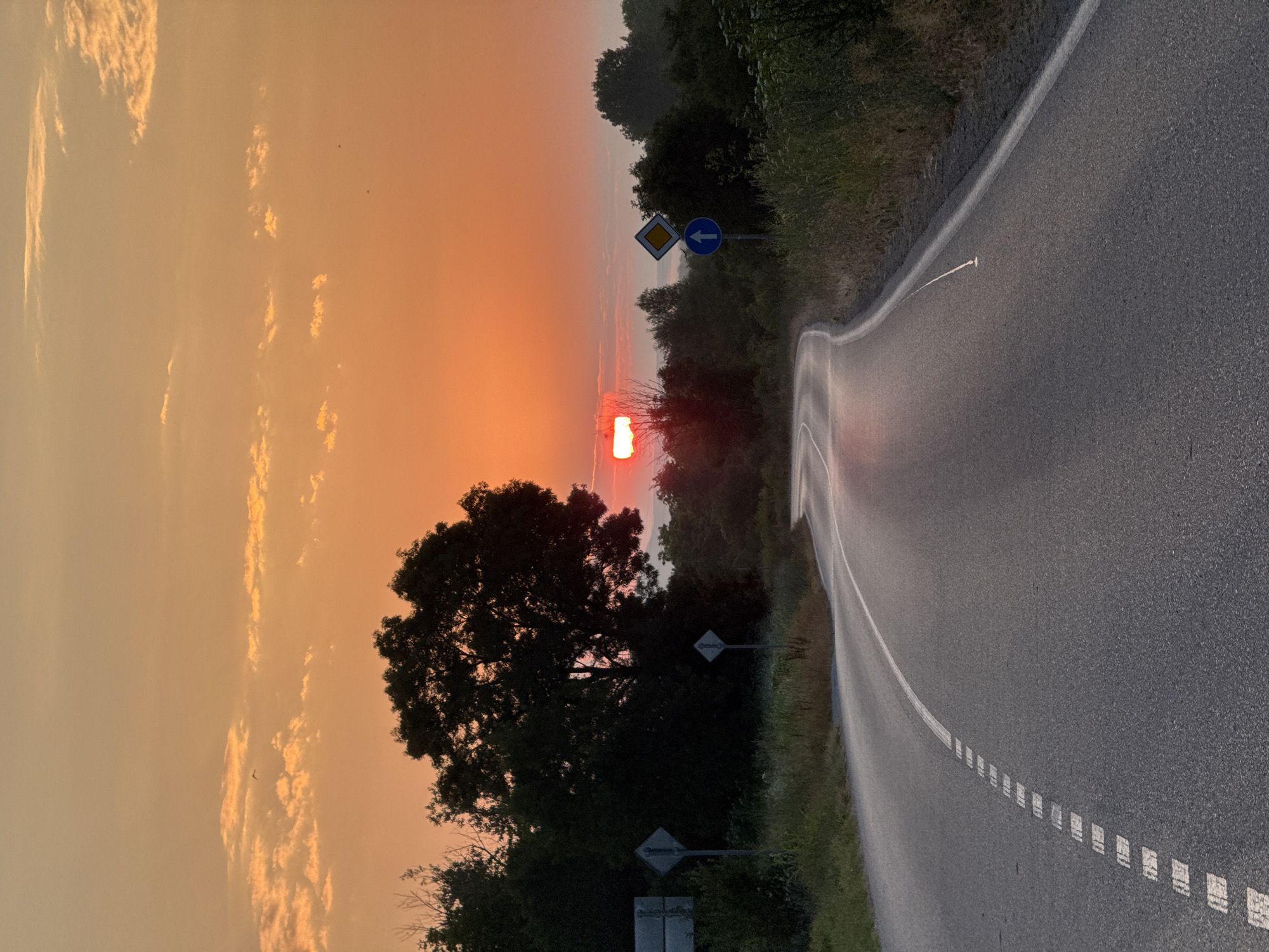 Winding rural road under a warm sunset sky