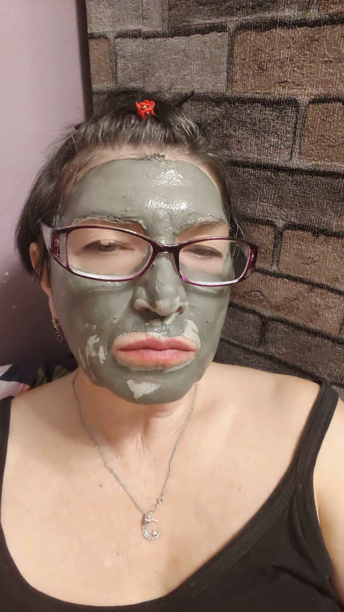 Woman applies clay facial mask during skincare routine in Krasnoyarsk