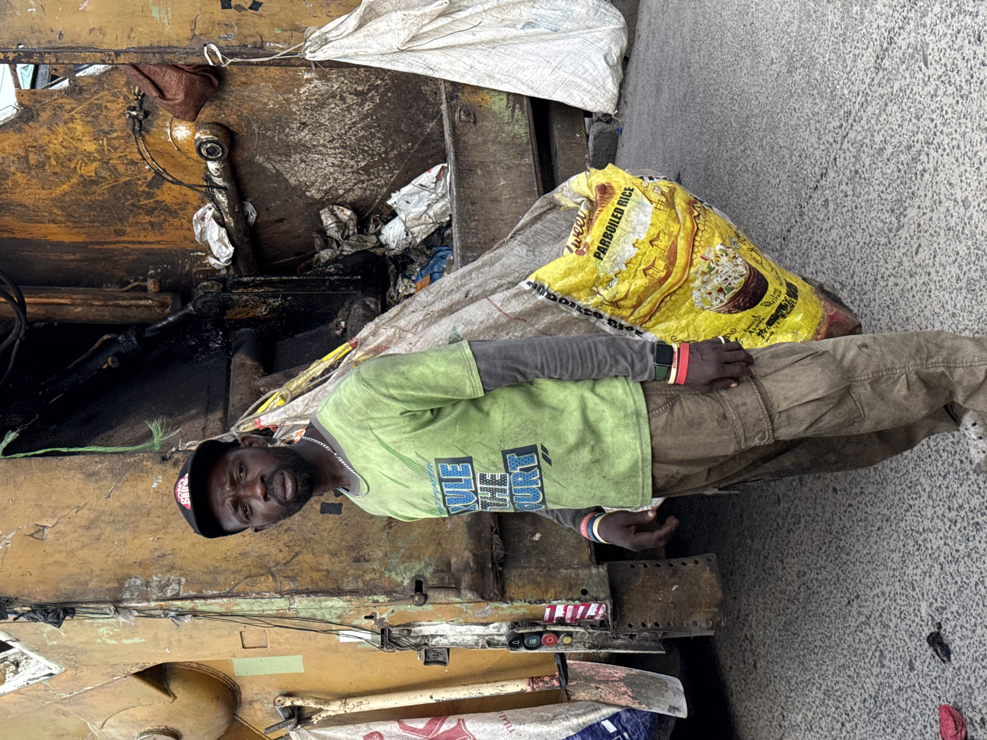 Man stands beside garbage truck during collection in Ado
