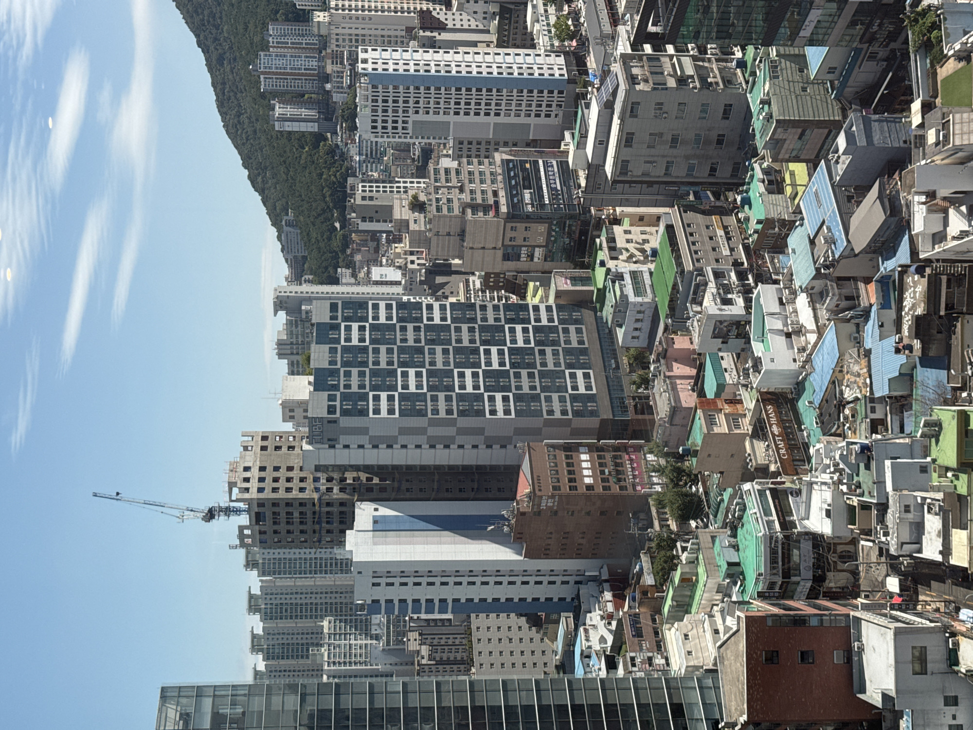 Aerial views over Busan's dense urban skyline and mountain backdrop