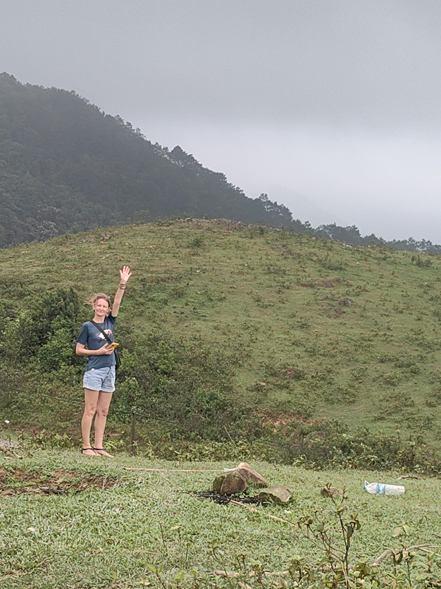 Woman waves near resting water buffalo in Vietnamese commune