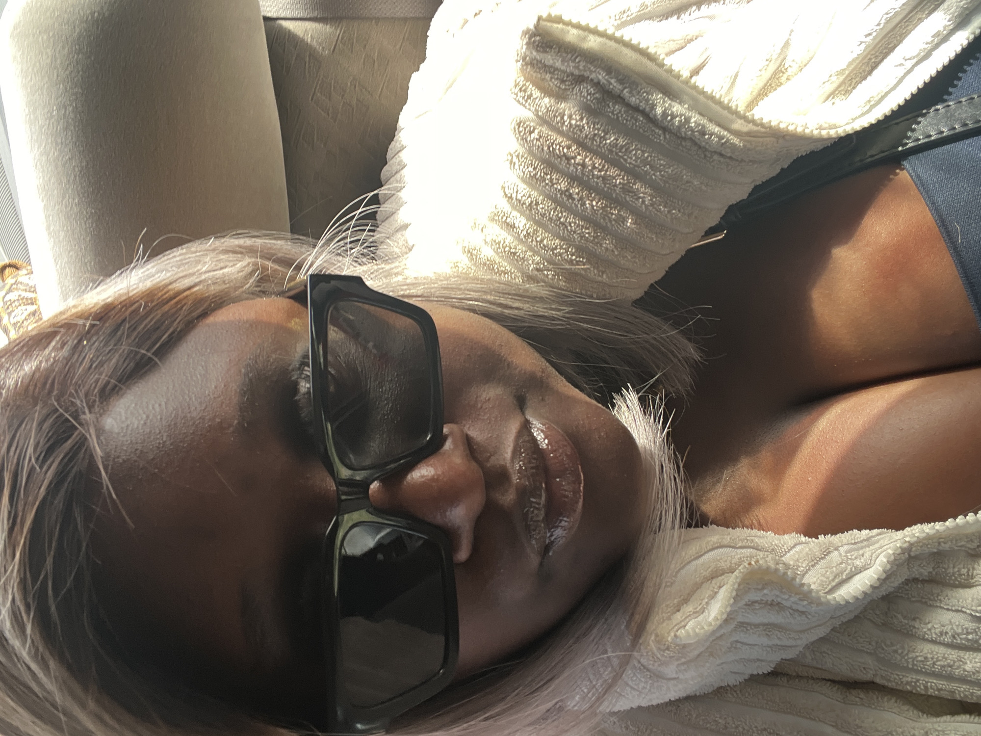Woman rests in vehicle wearing sunglasses in Nabatum, Nigeria