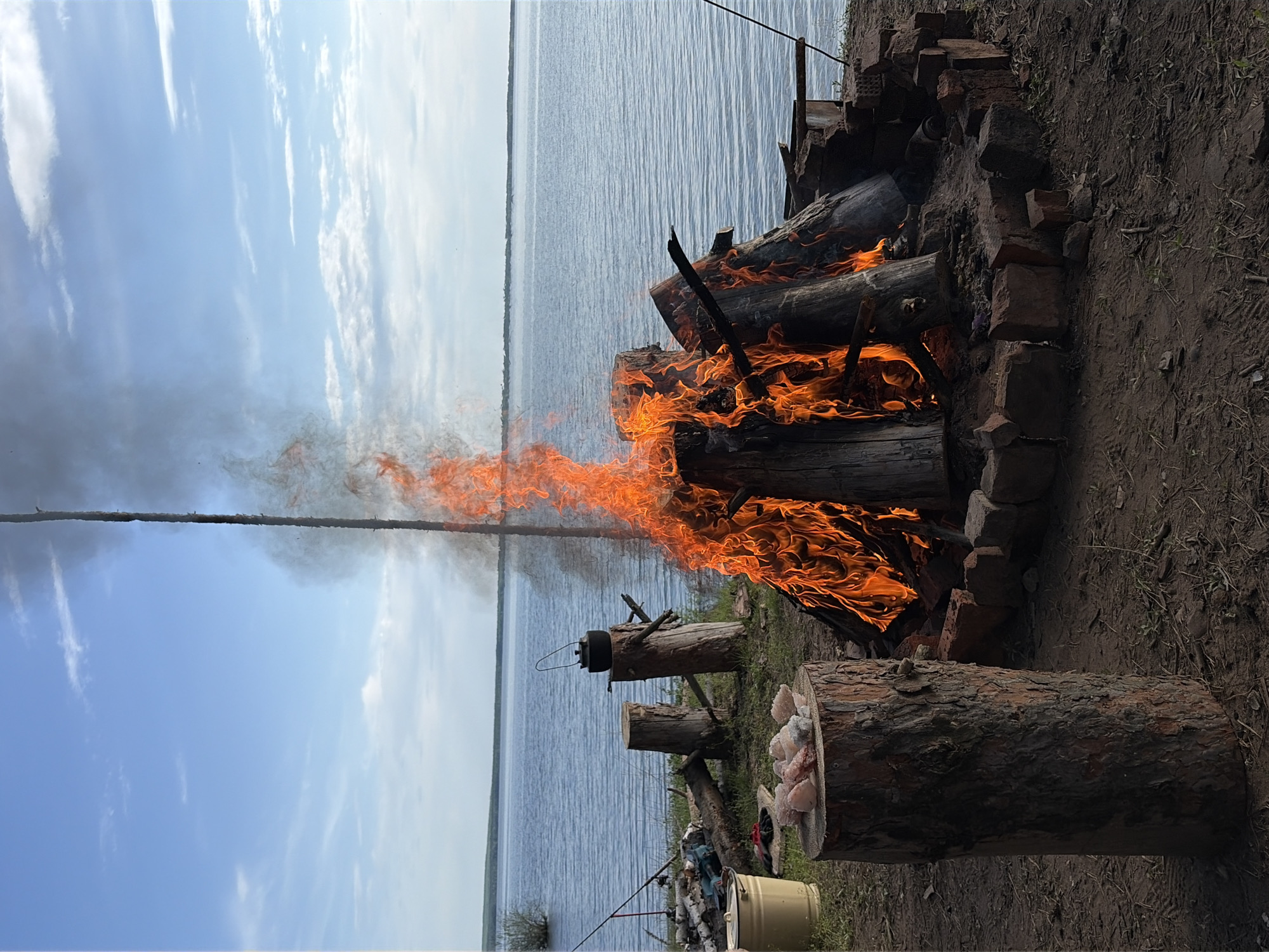 Campfire burns beside water in Zabegaevo, Russia