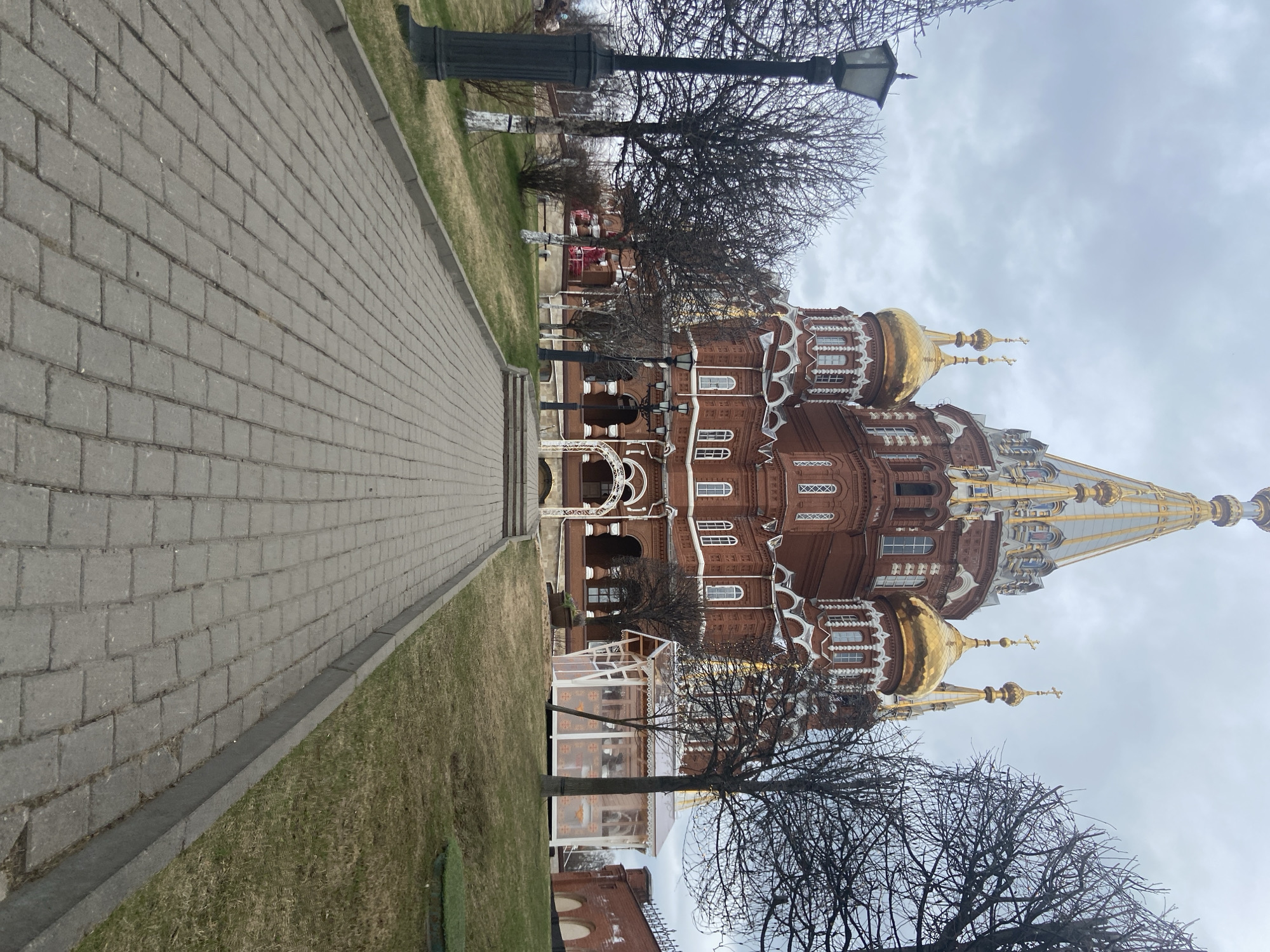 Brown brick building with golden domes observed under overcast sky
