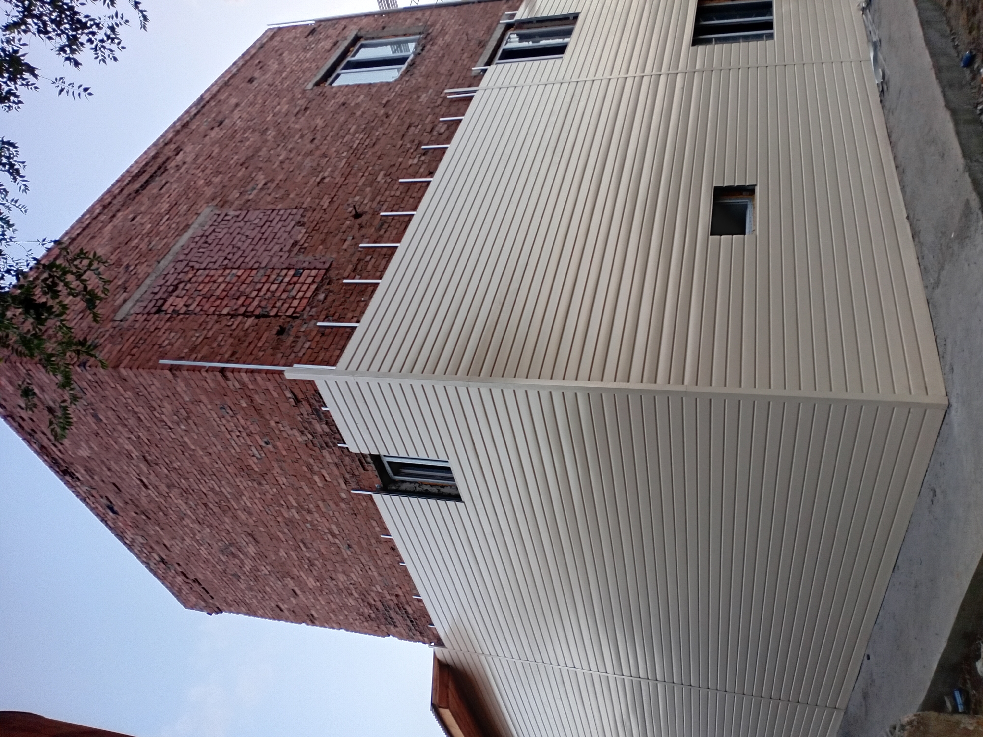 Brick building getting vinyl siding in Semey, Kazakhstan