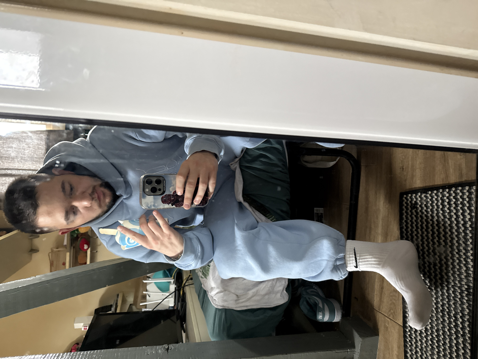 Man takes mirror selfies in light blue hoodie in Sofia
